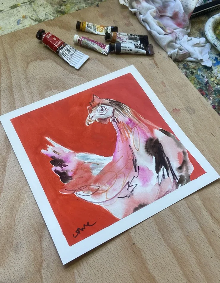 A colourful chicken painting by Catherine Jennifer, on the artist's painting table, with tubes of paint in the background.