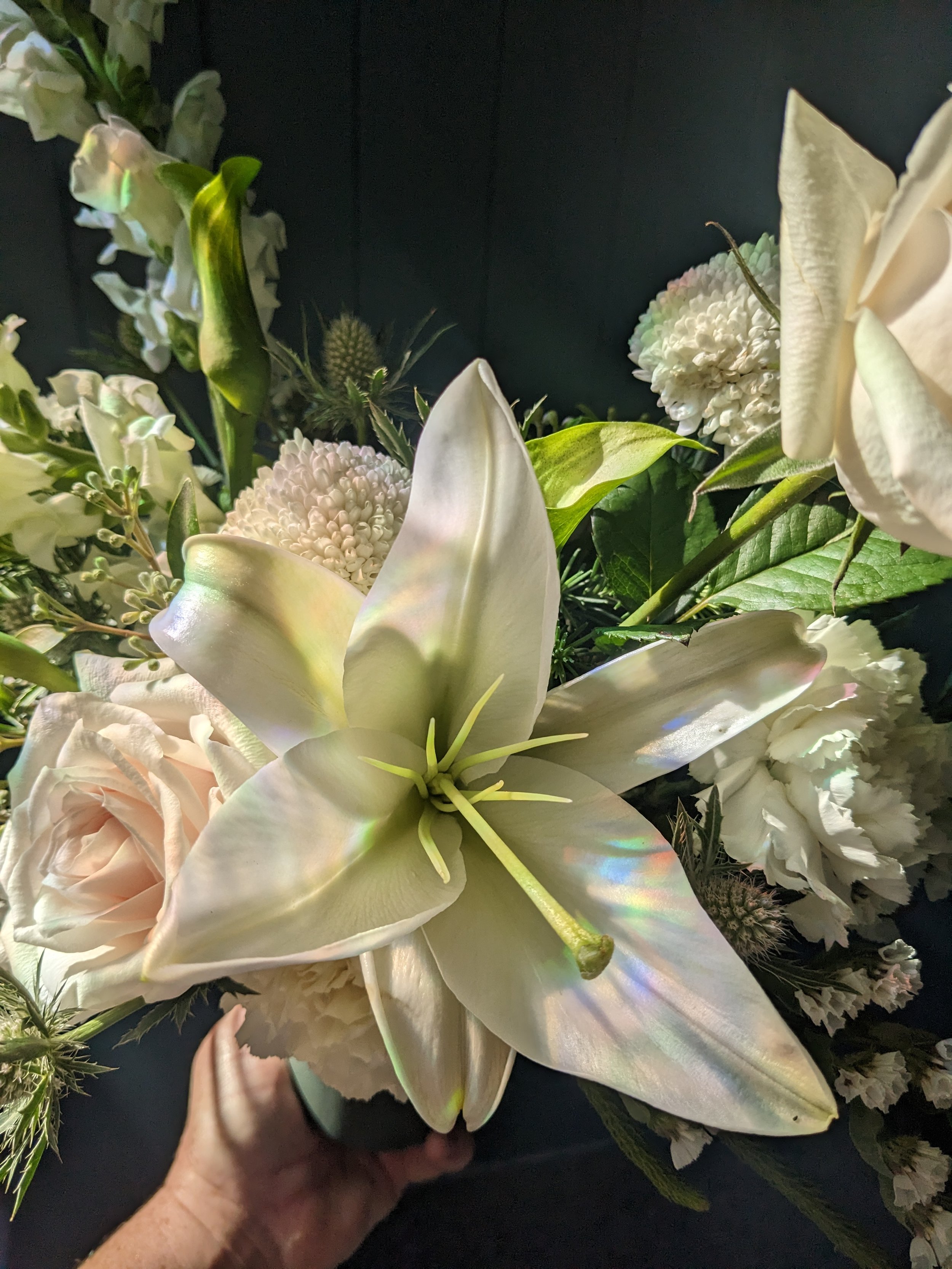 Fresh white and green flowers, arranged in a dark green ceramic vase. Featuring Roses, Snapdragons and Lily.