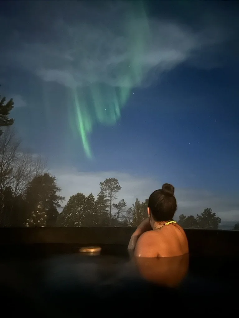 Guest watching the Northern Lights from ACIN's outdoor DROP jacuzzi in Malangen