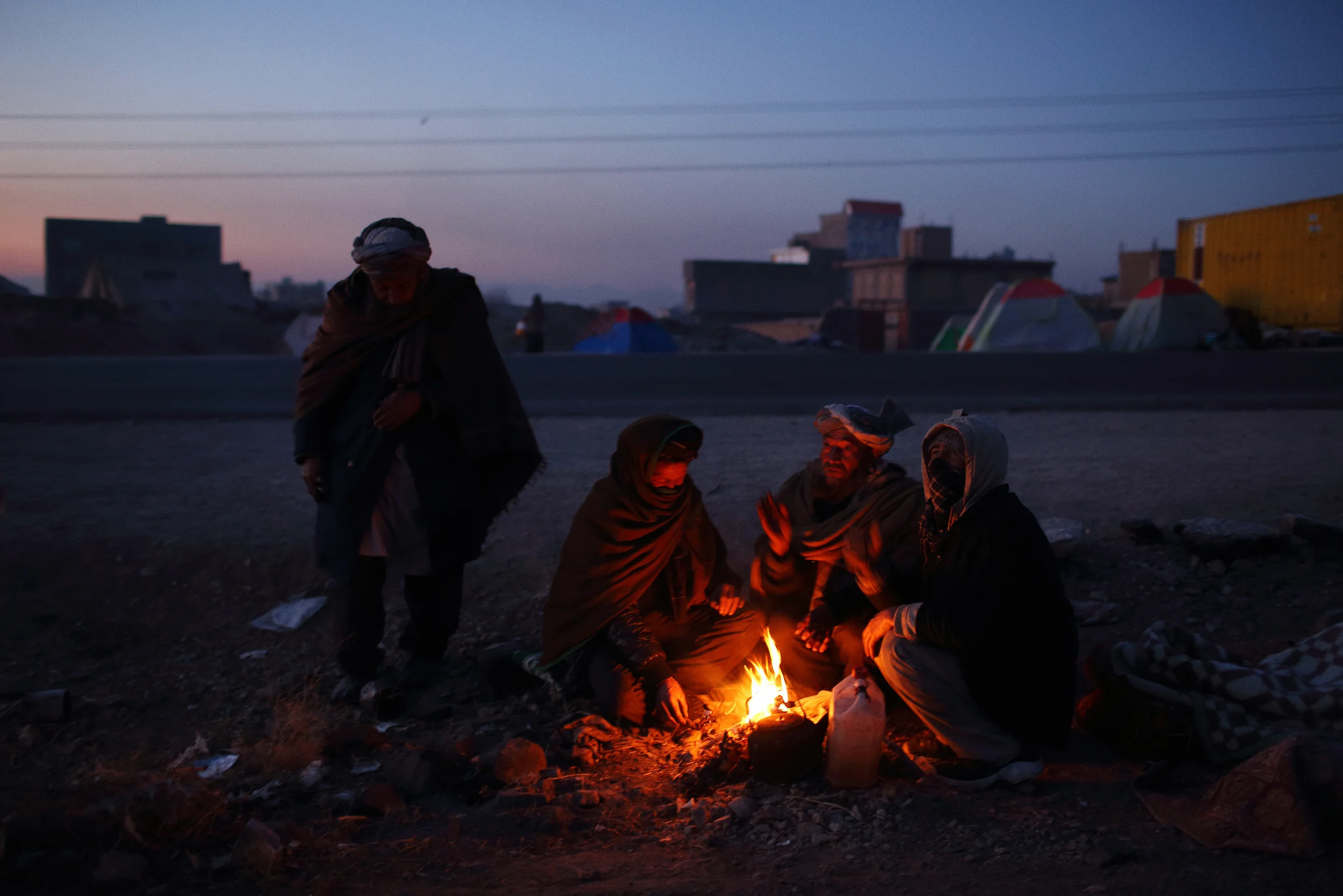  Displaced by fighting and drought from their home province of Ghor and with temperatures well below freezing, men warm themselves around a fire at dawn by a highway where they and some 300 others had set up an informal camp. Herat, December 2013 