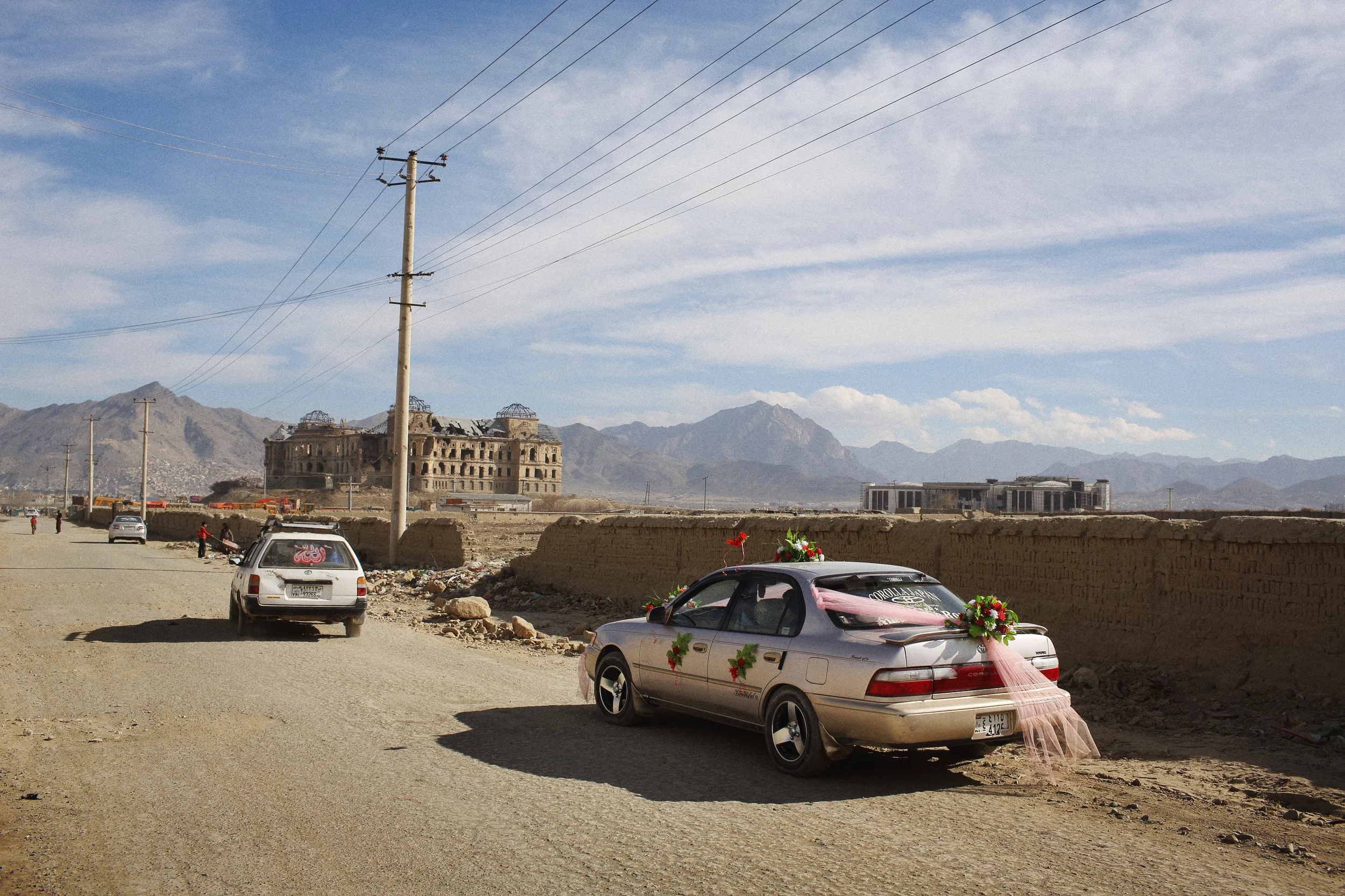  A wedding car drives toward the century-old Darulaman Palace on the southern outskirts of Kabul. The palace was badly damaged during the civil war of the 1990s. The foundations of the new national parliament building, financed by India, can be seen 