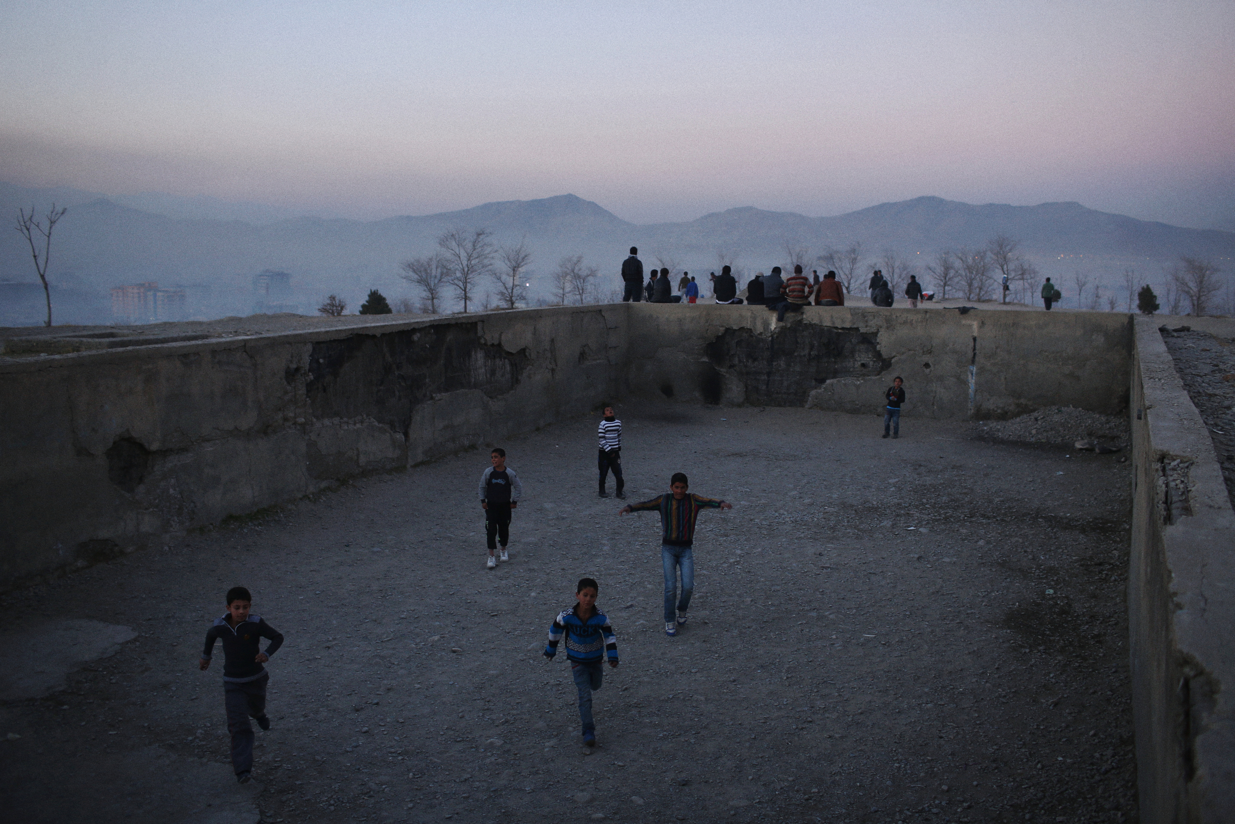  Young boys play football in one of the many derelict Soviet-era swimming pools that punctuate hilltops around Kabul. Kabul, December 2013 