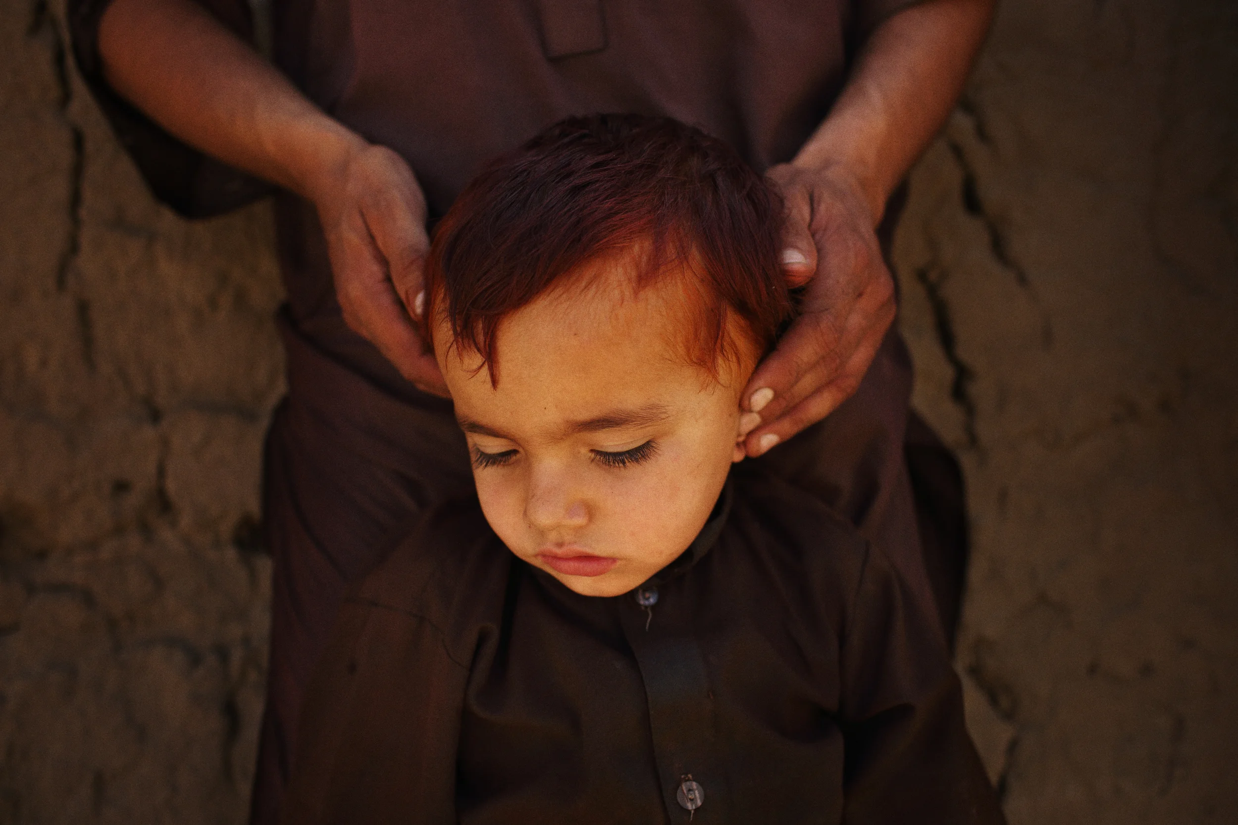  Four-year-old Jawad’s ears are blocked by his uncle in order to protect them from the noise of a fire fight between Afghan National Police and Taliban fighters. Jawad and several other passing civilians had become trapped by the fighting that follow