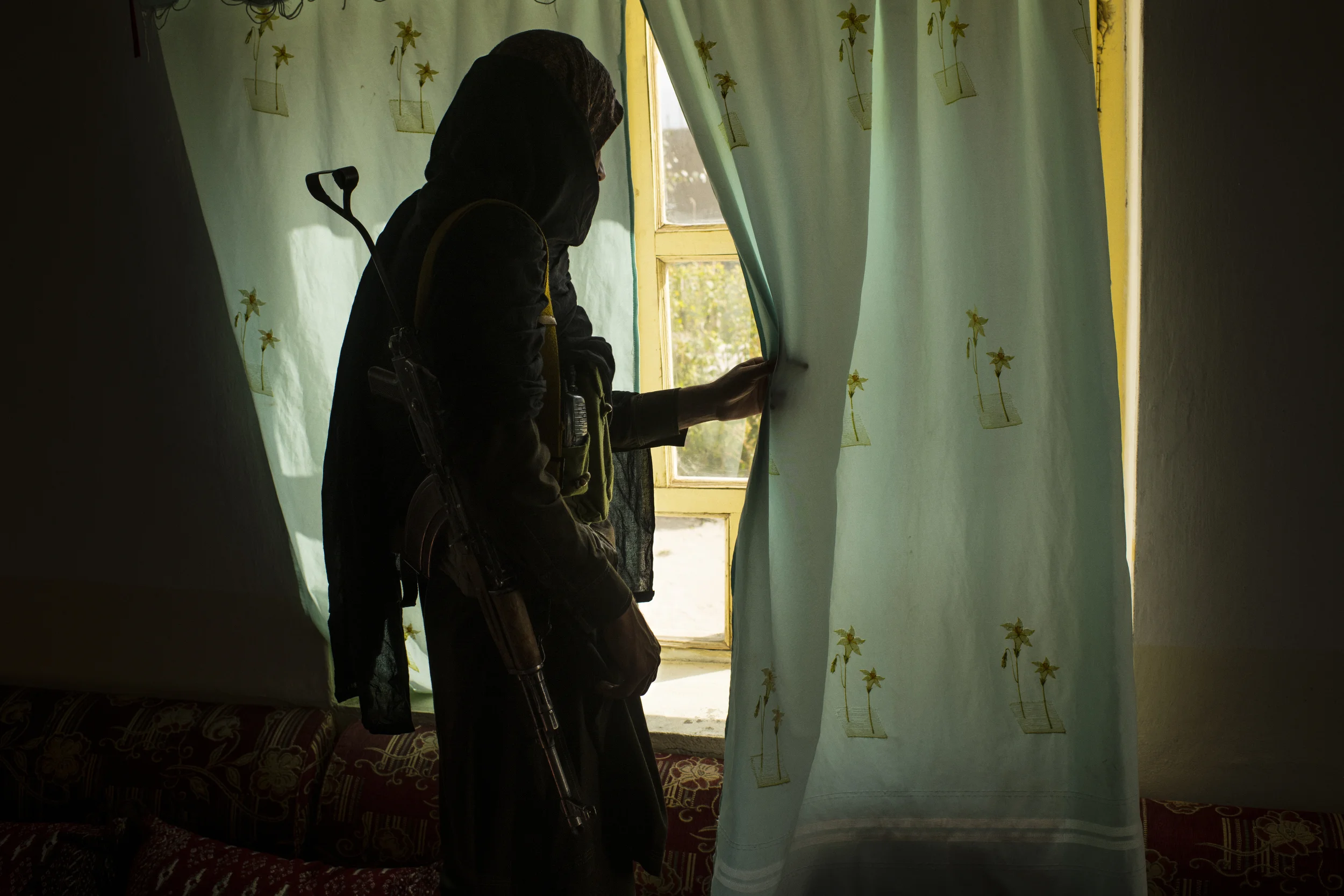  Yamin (pseudonym), a local Taliban fighter and bodyguard of a commander who went by the name of Mullah Abdul Saeed and says he is responsible for 150 men in nearby Charkh District, checks out the window before departing a house on the edge of a vill