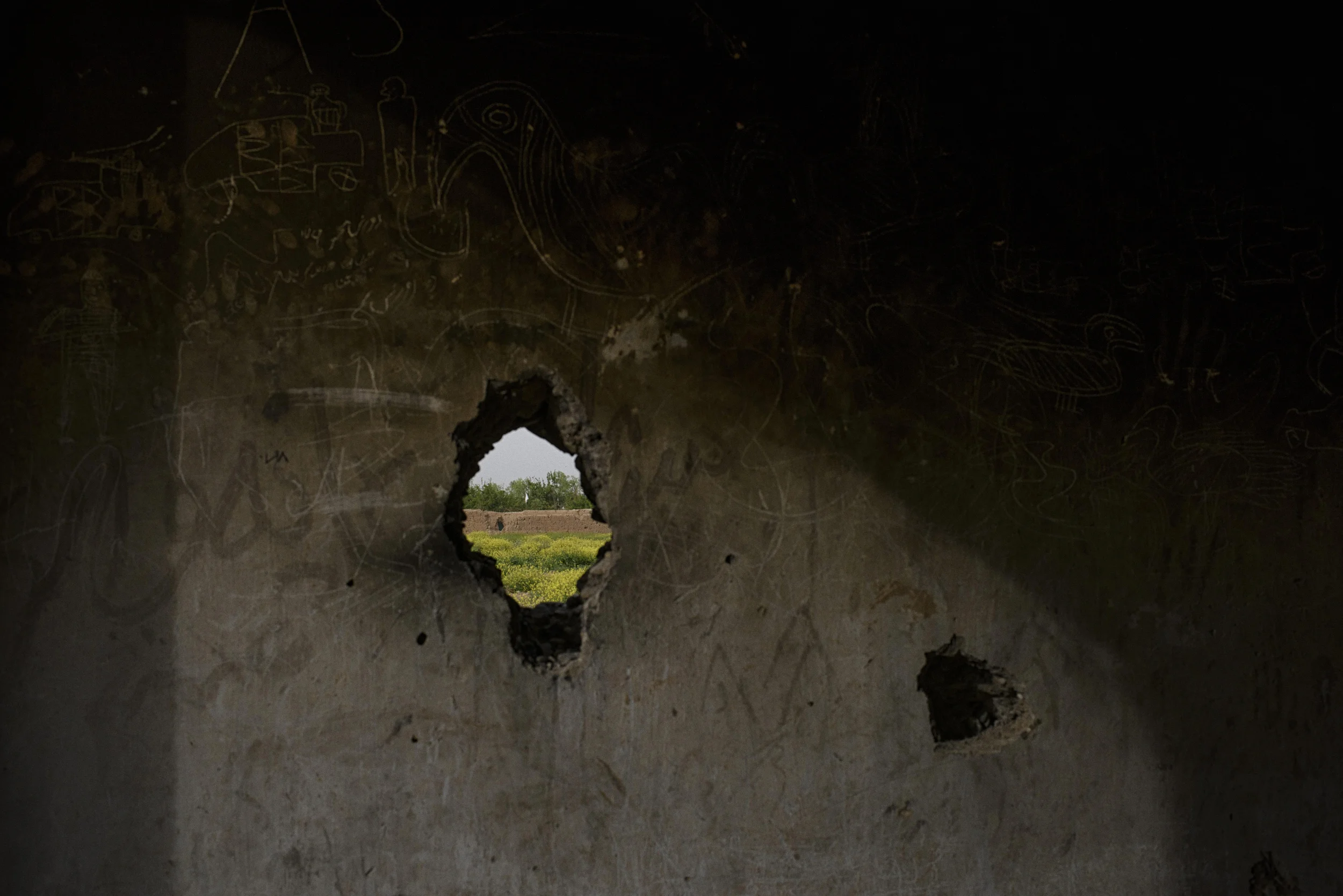  A Taliban flag seen through a sniper hole made in the wall of a school that the Afghan National Army had commandeered in Chahr-i Anjir, just outside Lashkar Gah. Chahr-i Anjir would be overrun by the Taliban weeks later, bringing the fighters within