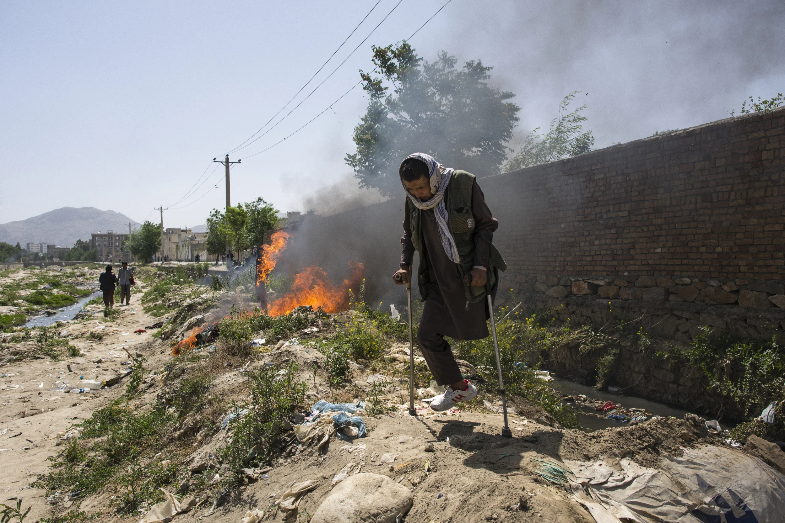  In the dry Kabul River-bed, near the famous addict hub of Pul-i Sorkhta, or Burnt Bridge, plain clothed police destroy the makeshift shelters of addicts, including one belonging to a woman and another to an amputee addict. Kabul, May, 2017. 