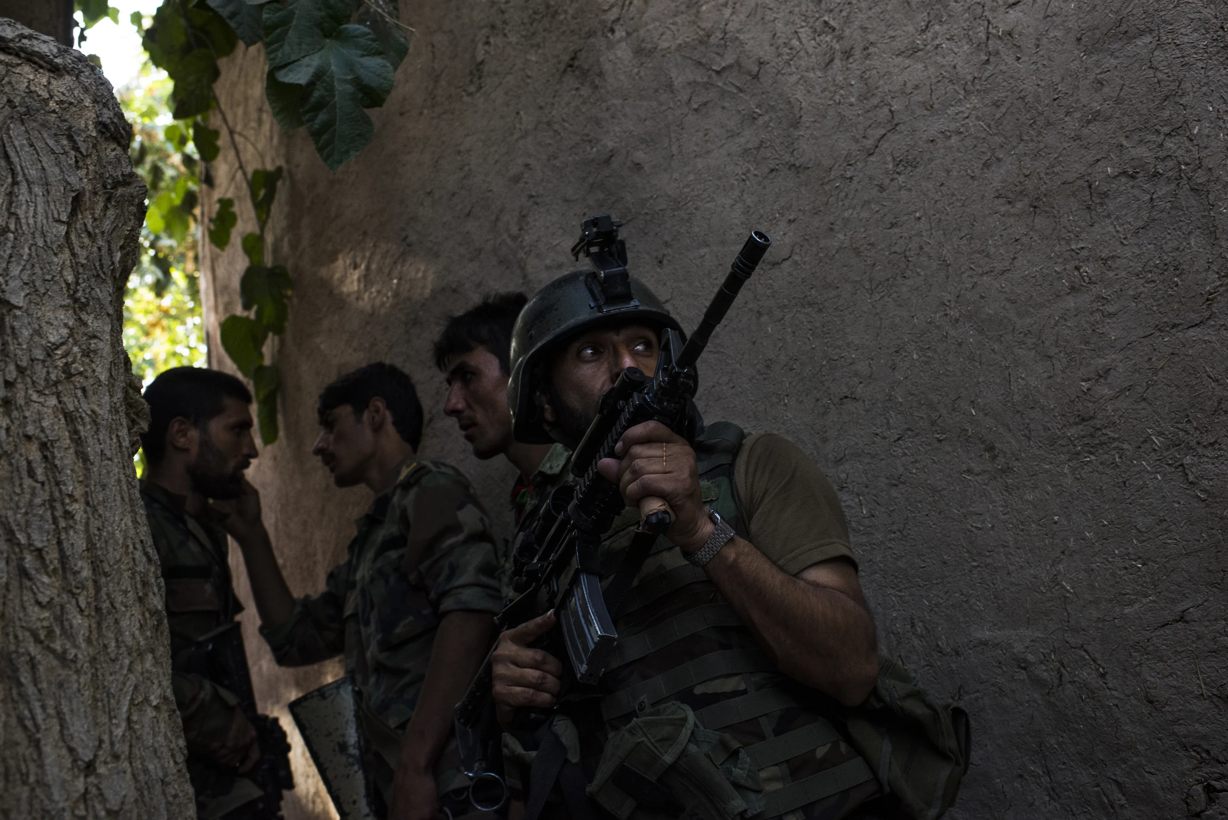  An Afghan commando covers regular Afghan National Army soldiers from a Taliban ambush on their compound during which, one, at left, was shot in the neck but avoided serious injury. Helmand Province, August, 2016. 