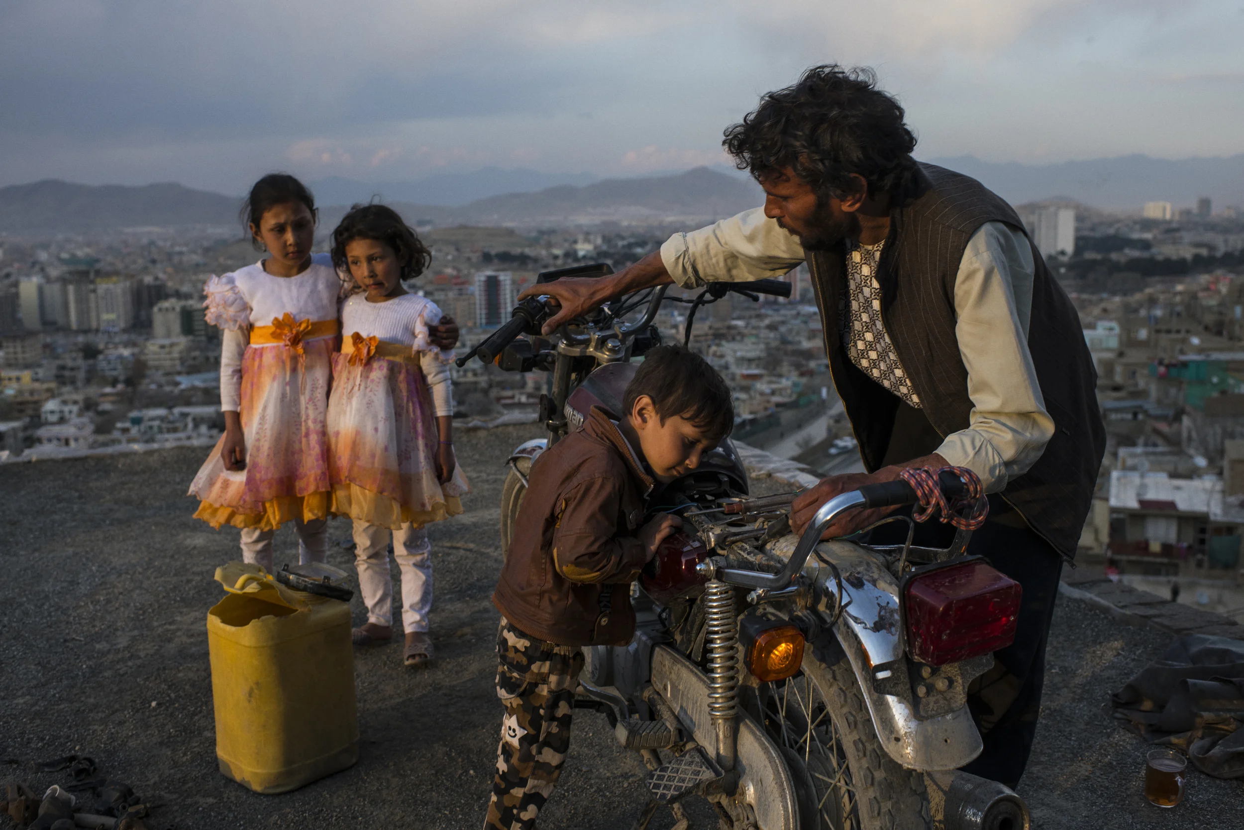  Mustafa was helped with motorcycle maintenance by his son Nasir while his daughters Rukia and Giti wore the new dresses they’d bought to celebrate Nawroz, the Persian New Year. Kabul, March, 2018. 