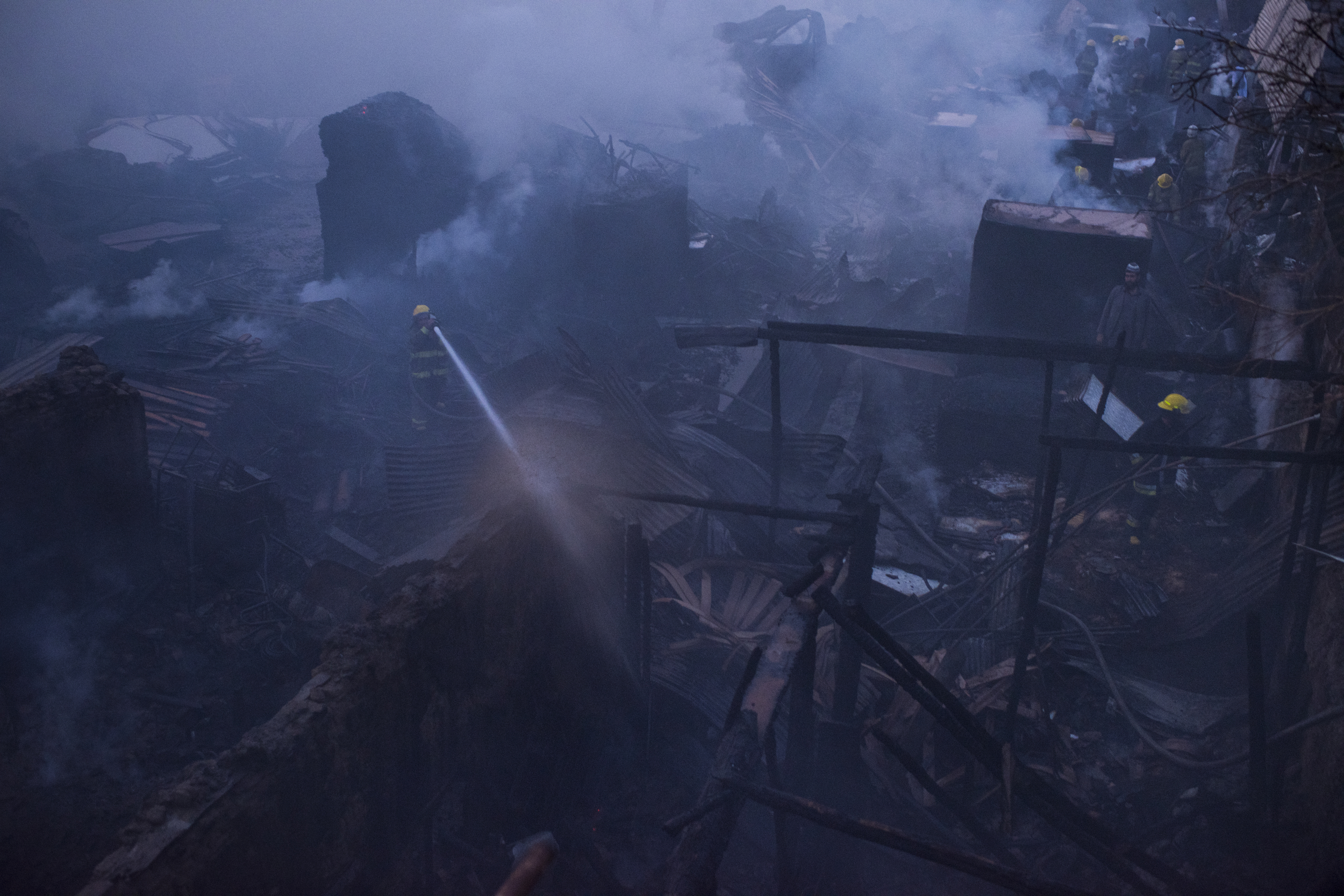  A fire fighter douses the smouldering ruins of a timber bazaar that caught fire 10 hours earlier. Kabul, September, 2016. 