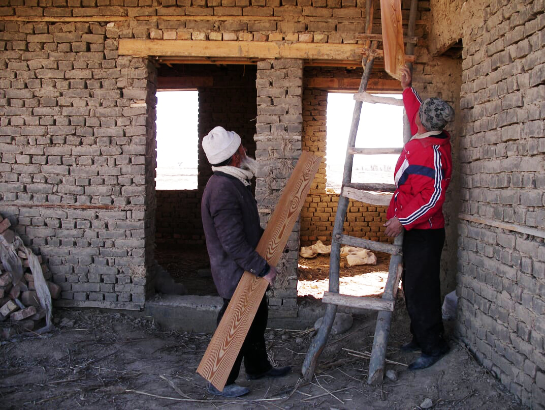  Food-for-work workers passing beams up for the roof 