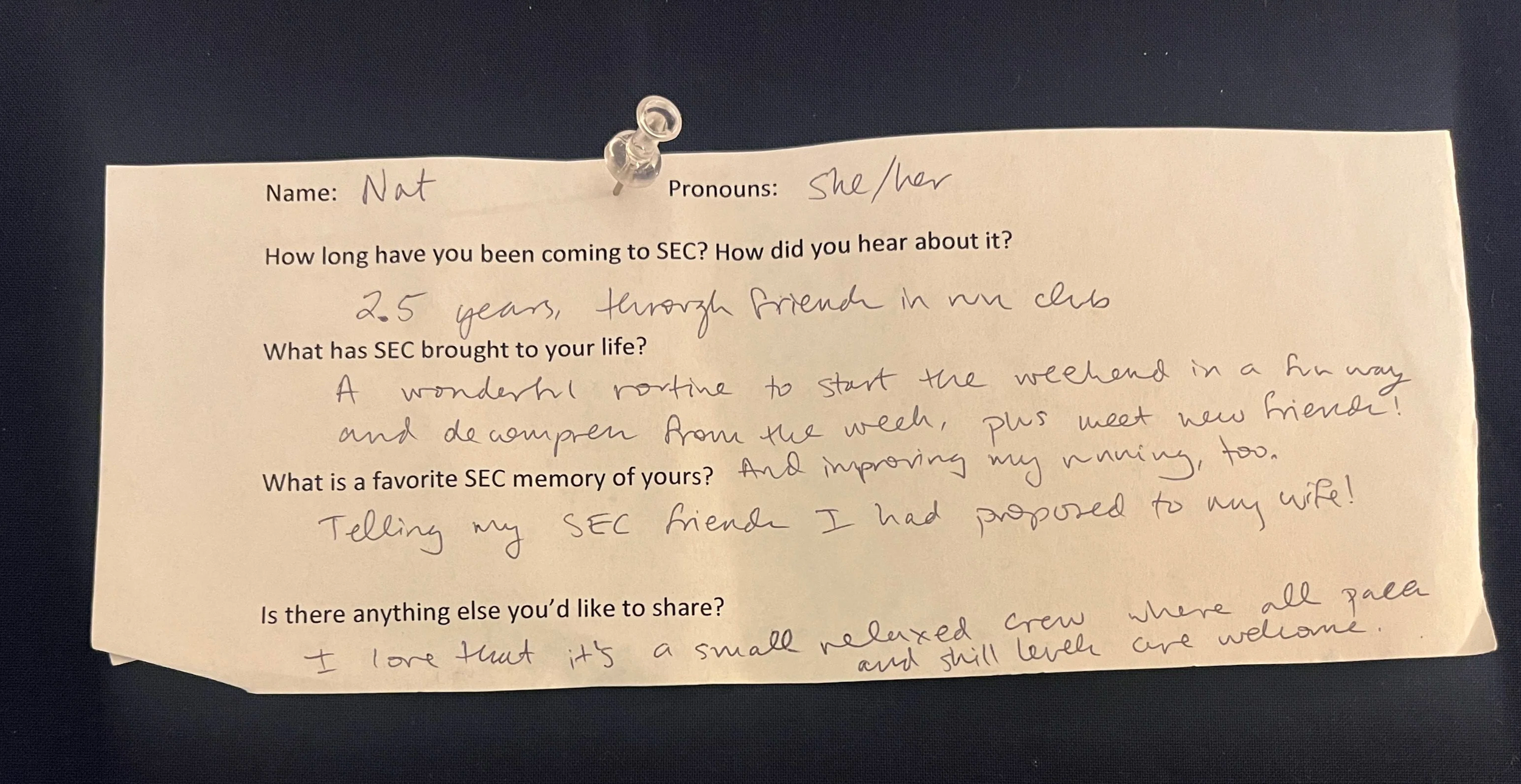 An image of a slip of paper with typed questions and hand written answers. The paper is pinned to a navy blue background with a clear thumbtack. The contents of the writing are written below the photo.