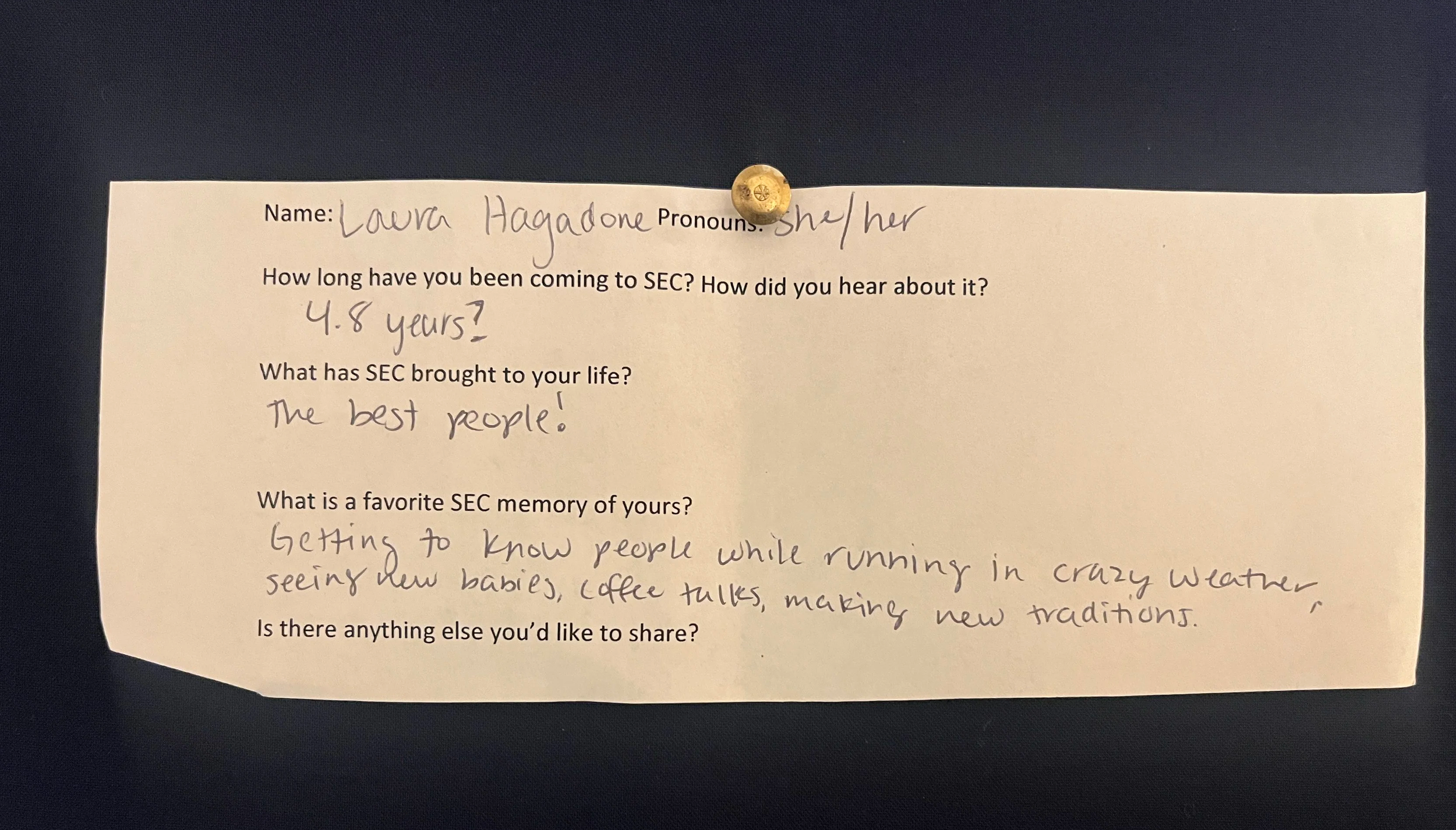 An image of a slip of paper with typed questions and hand written answers. The paper is pinned to a navy blue background with a gold metal thumbtack. The contents of the writing are written below the photo.