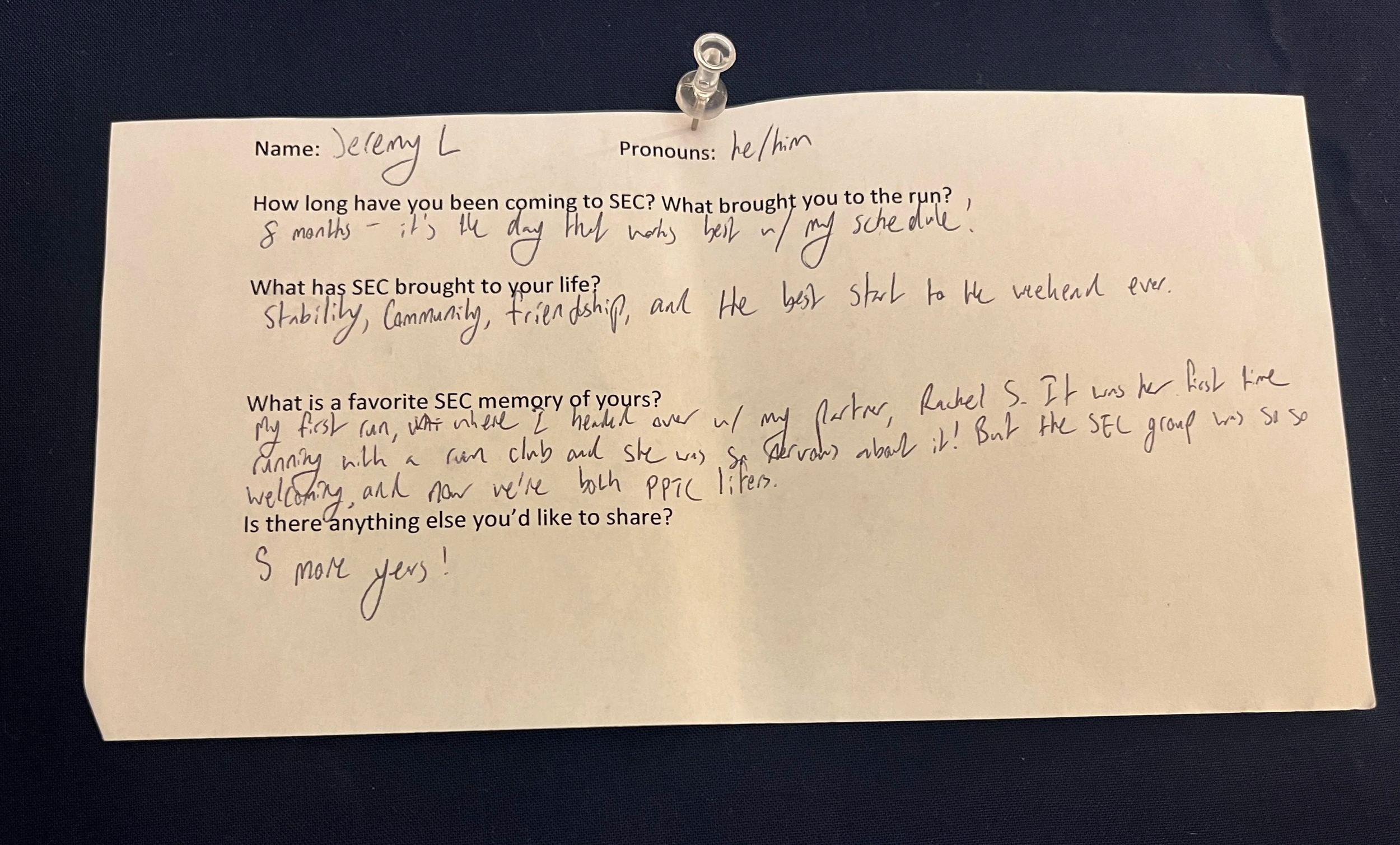 An image of a slip of paper with typed questions and hand written answers. The paper is pinned to a navy blue background with a clear thumbtack. The contents of the writing are written below the photo.