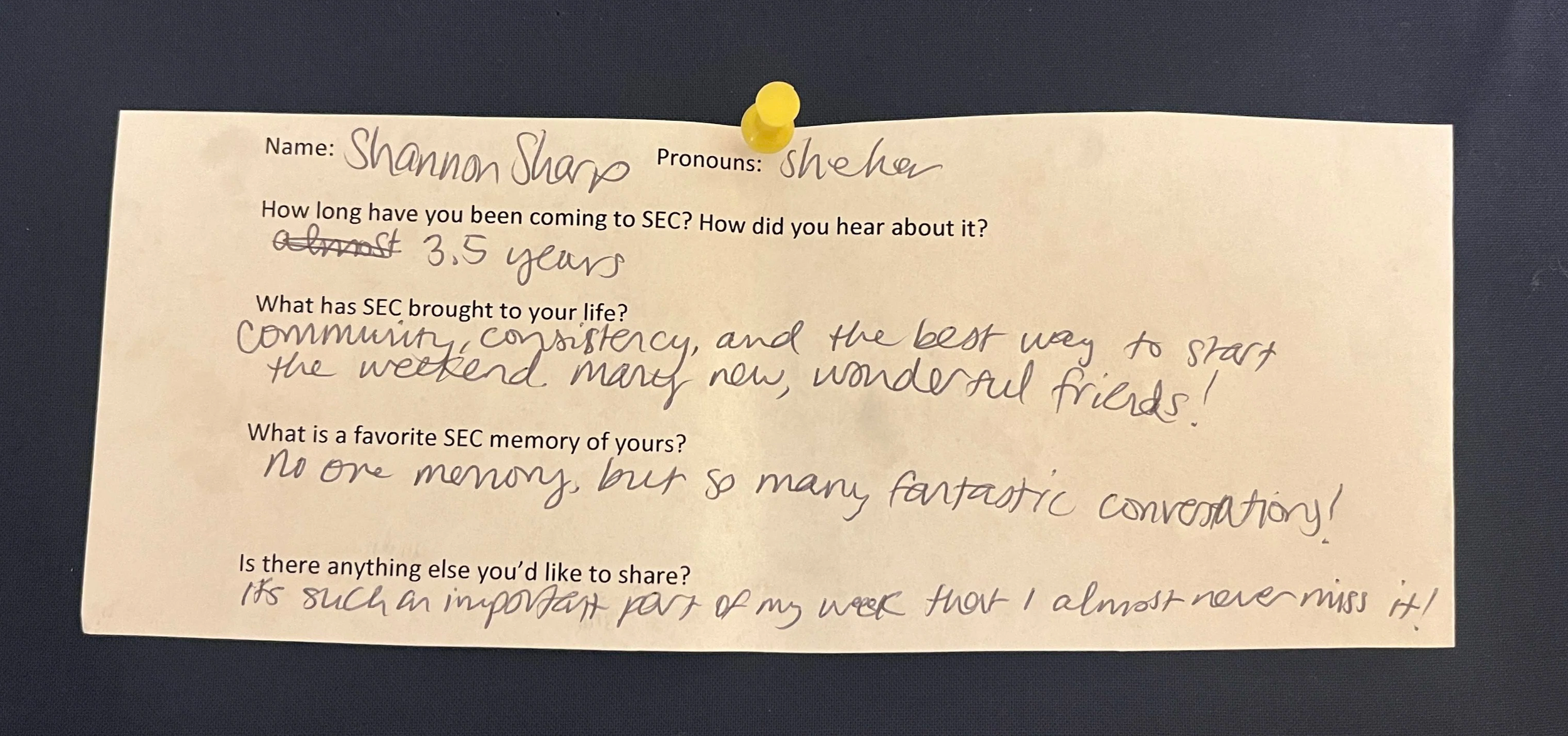 An image of a slip of paper with typed questions and hand written answers. The paper is pinned to a navy blue background with a yellow thumbtack. The contents of the writing are written below the photo.