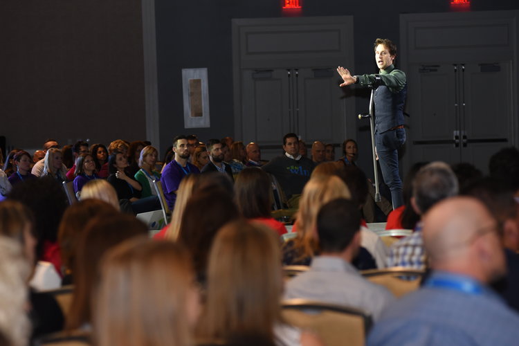 Inspirational speaker Josh Sundquist stands in the center of an audience, gesturing