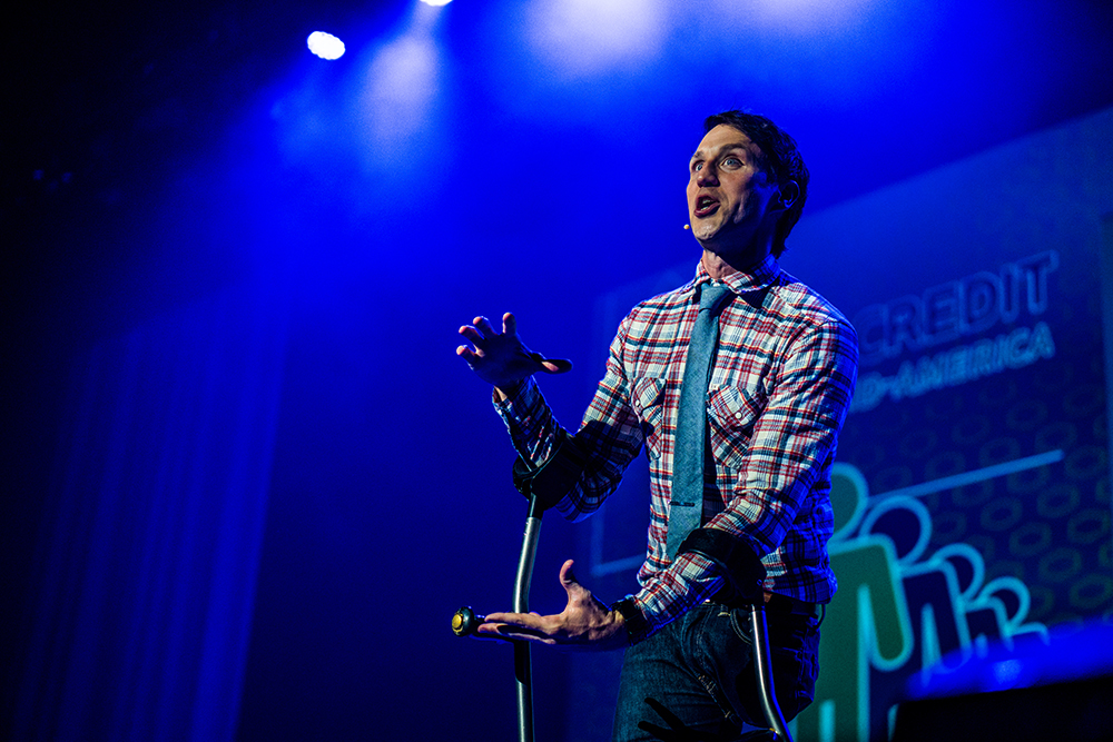 Josh gestures while on stage giving an inspirational speech