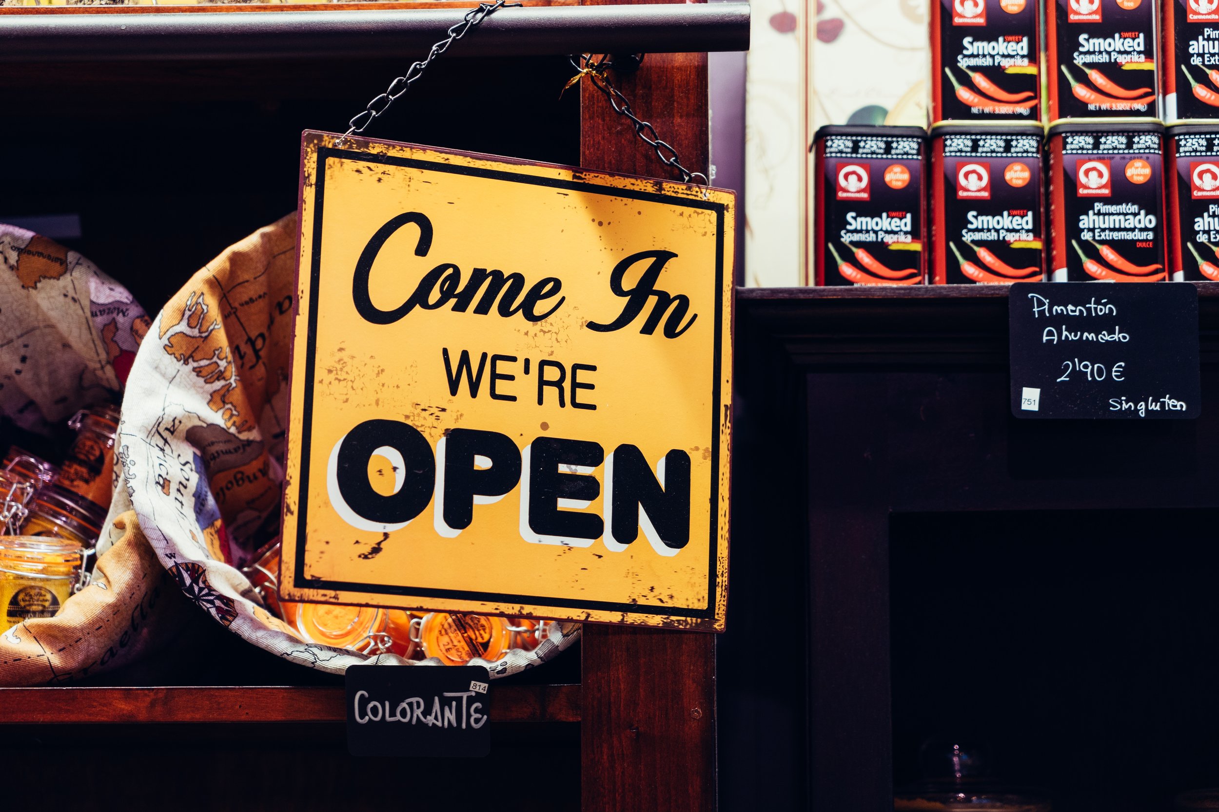  A bright yellow sign with the words “Come In we’re Open’ written on in  