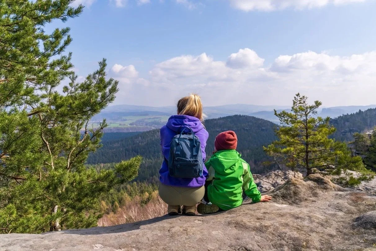 Adult and child stopped on a rock to admire expansive view