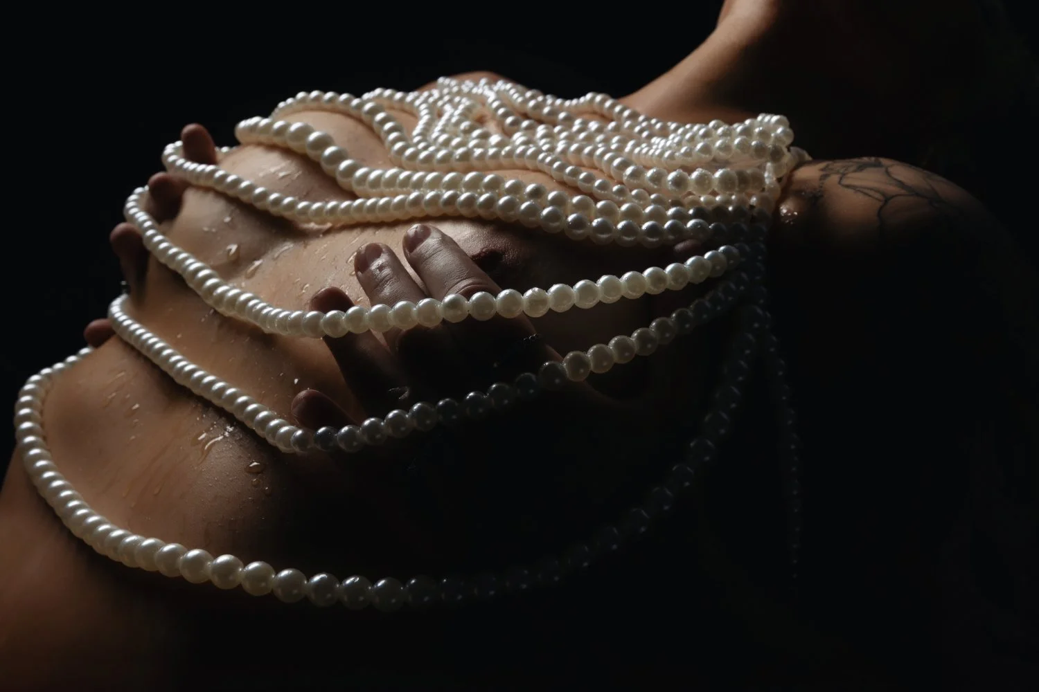 Woman posing with pearl accessories for a boudoir portrait
