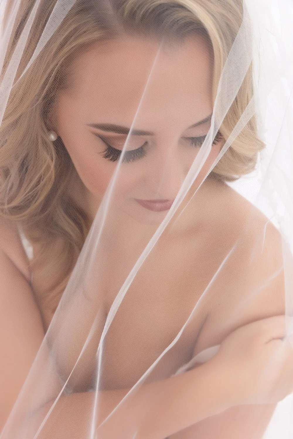 Woman posing with a bridal veil during a boudoir photoshoot