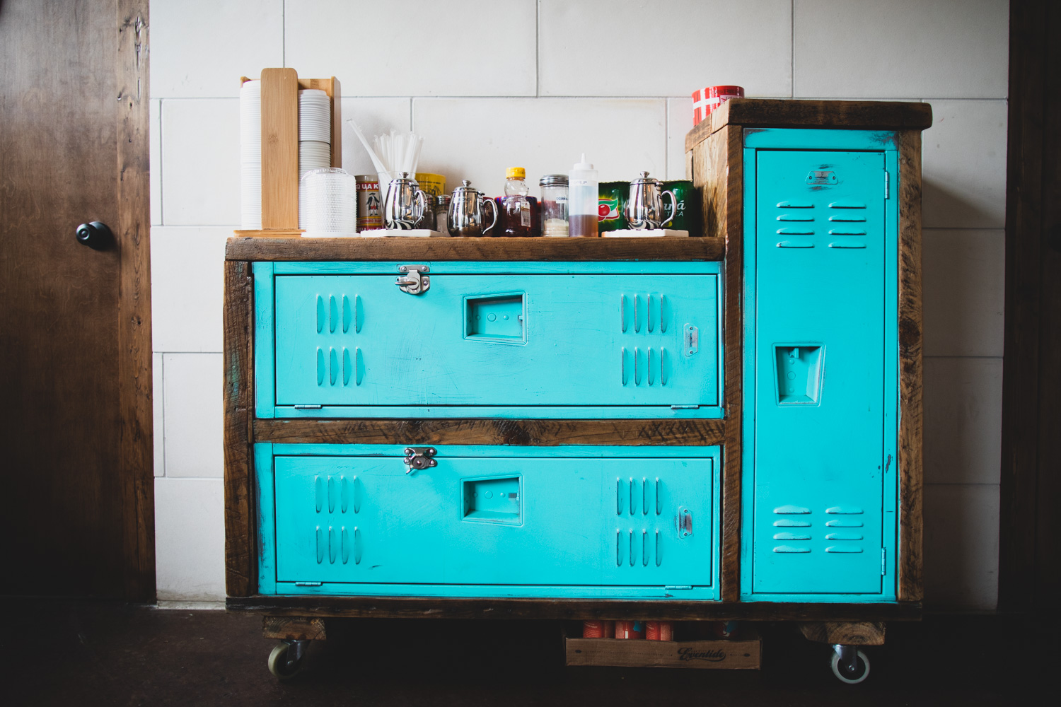 Old lockers beautifully repurposed to serve as a counter/storage/shelf for coffee lids, sugar, napkins, and other supplies.