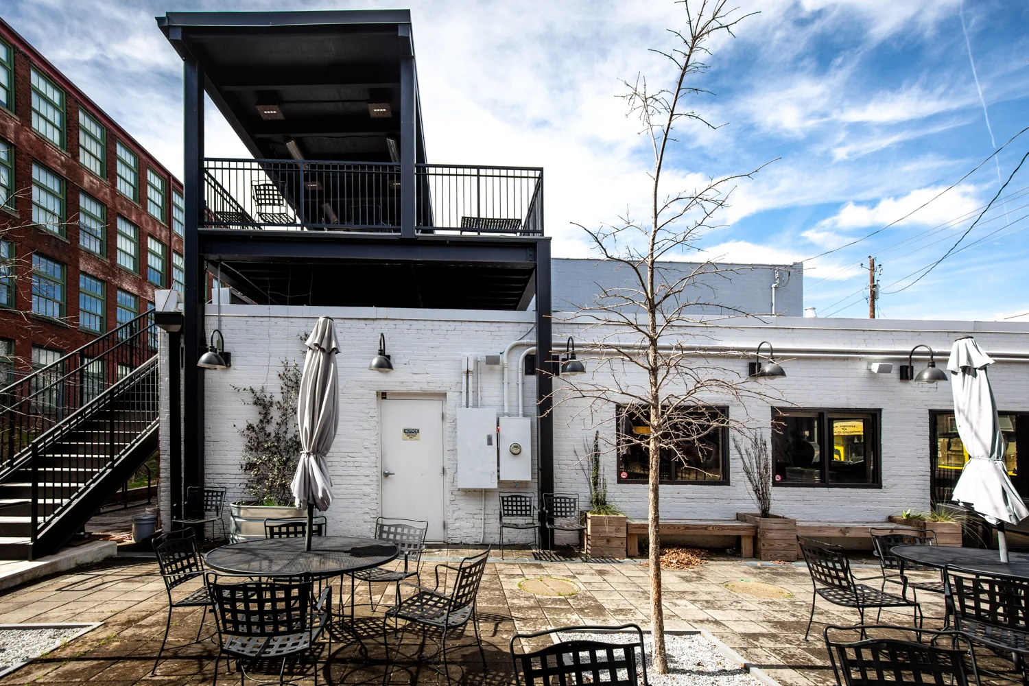 A view of the courtyard at Docent Coffee. There is plenty of outdoor seating and the space is pet-friendly! Note the stairs on the left leading to the second-floor patio with a covered roof.