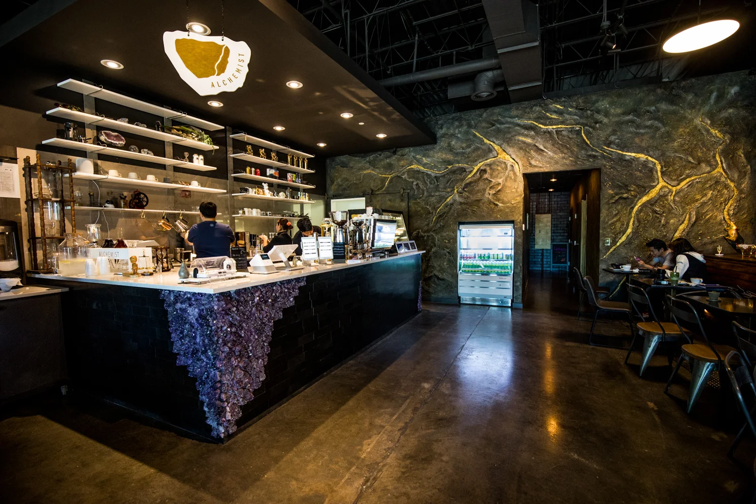 The central counter at Alchemist Trading Co. features a large amethyst gem at the corner.