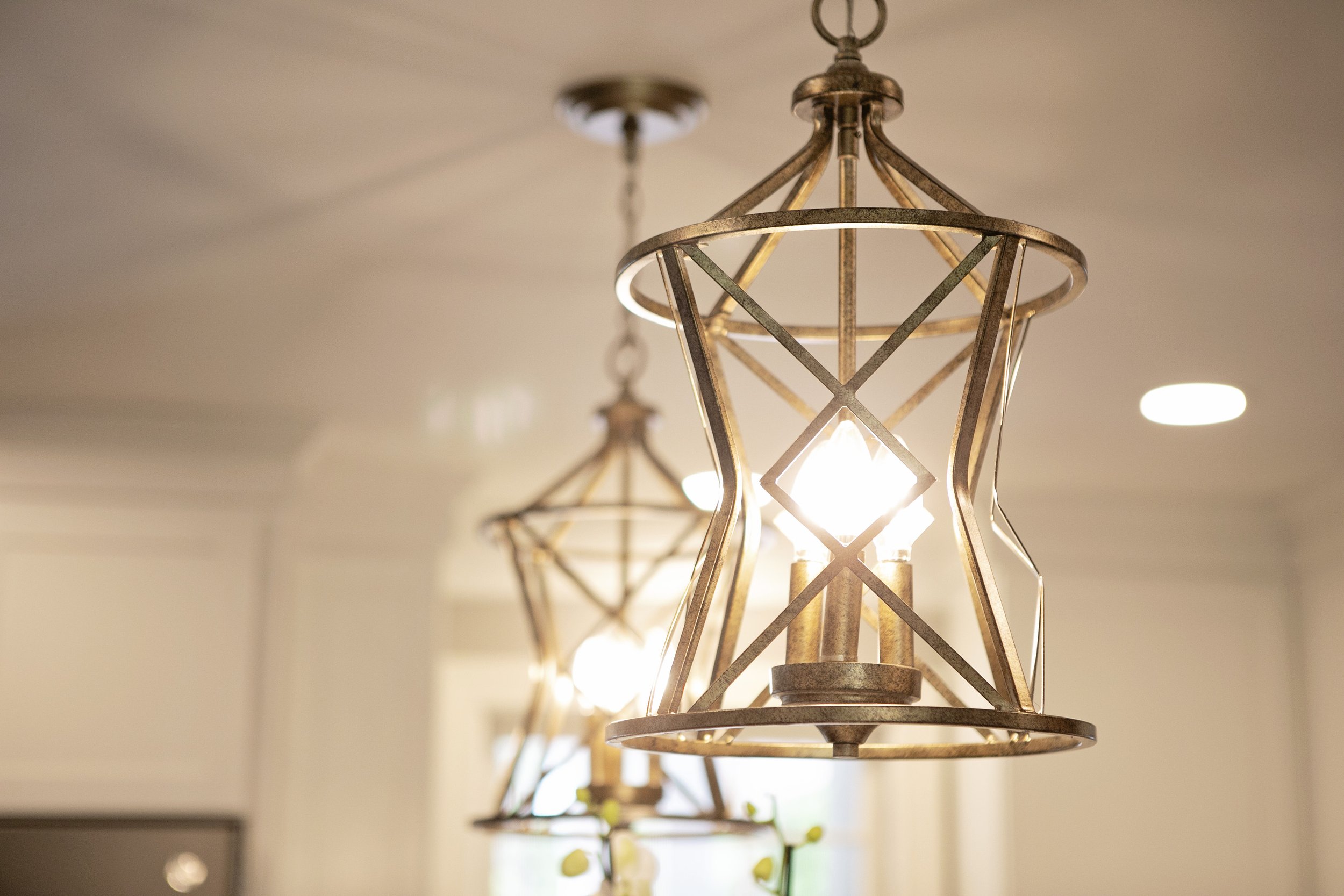 Two Millennium Lighting fixtures (Lakewood in Vintage Gold) hang centered over the kitchen island.