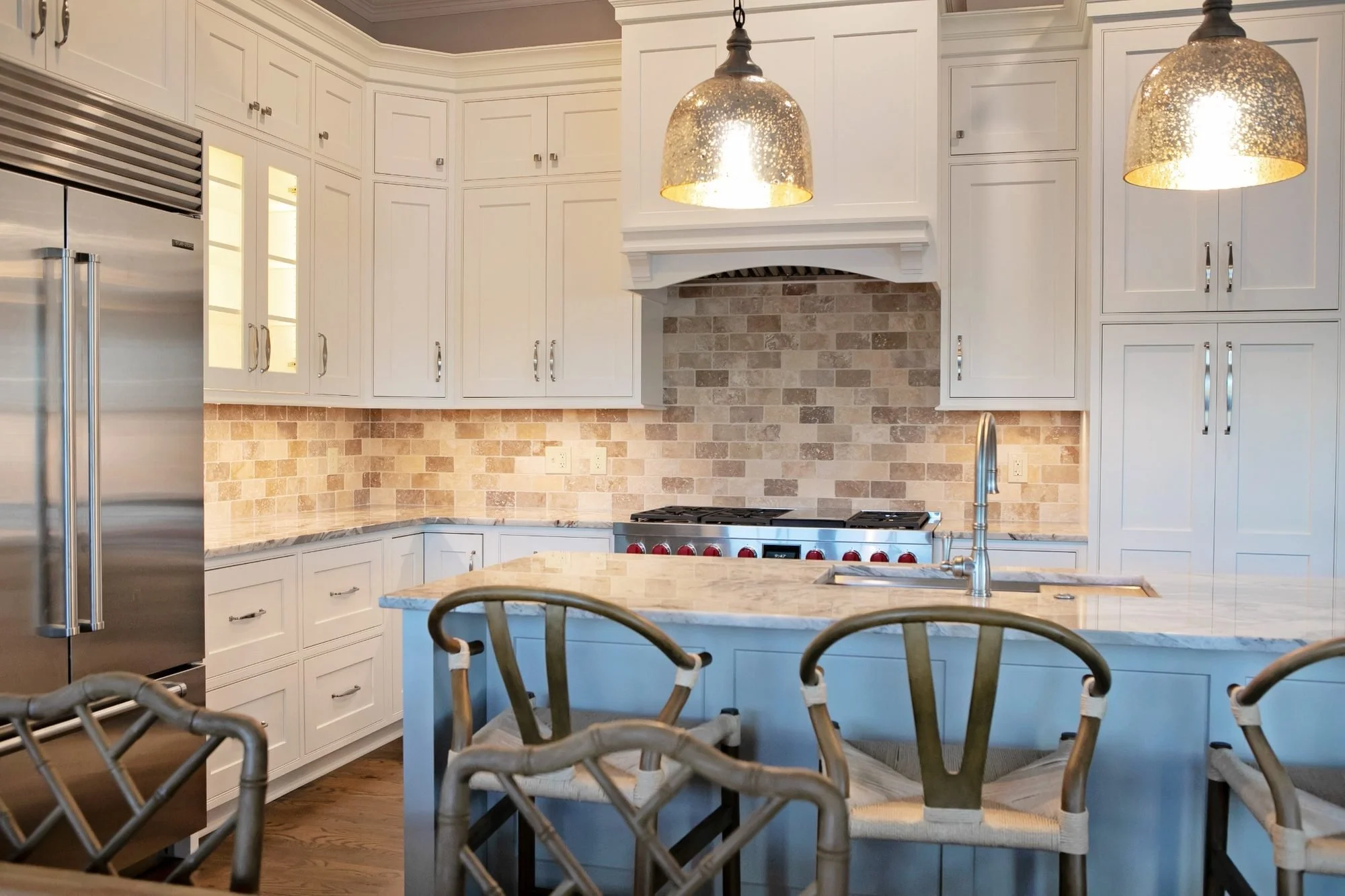 Lake Blackshear kitchen remodel in Warwick, GA, with white custom cabinetry, a large quartzite island, pendant lights, and bar seating.