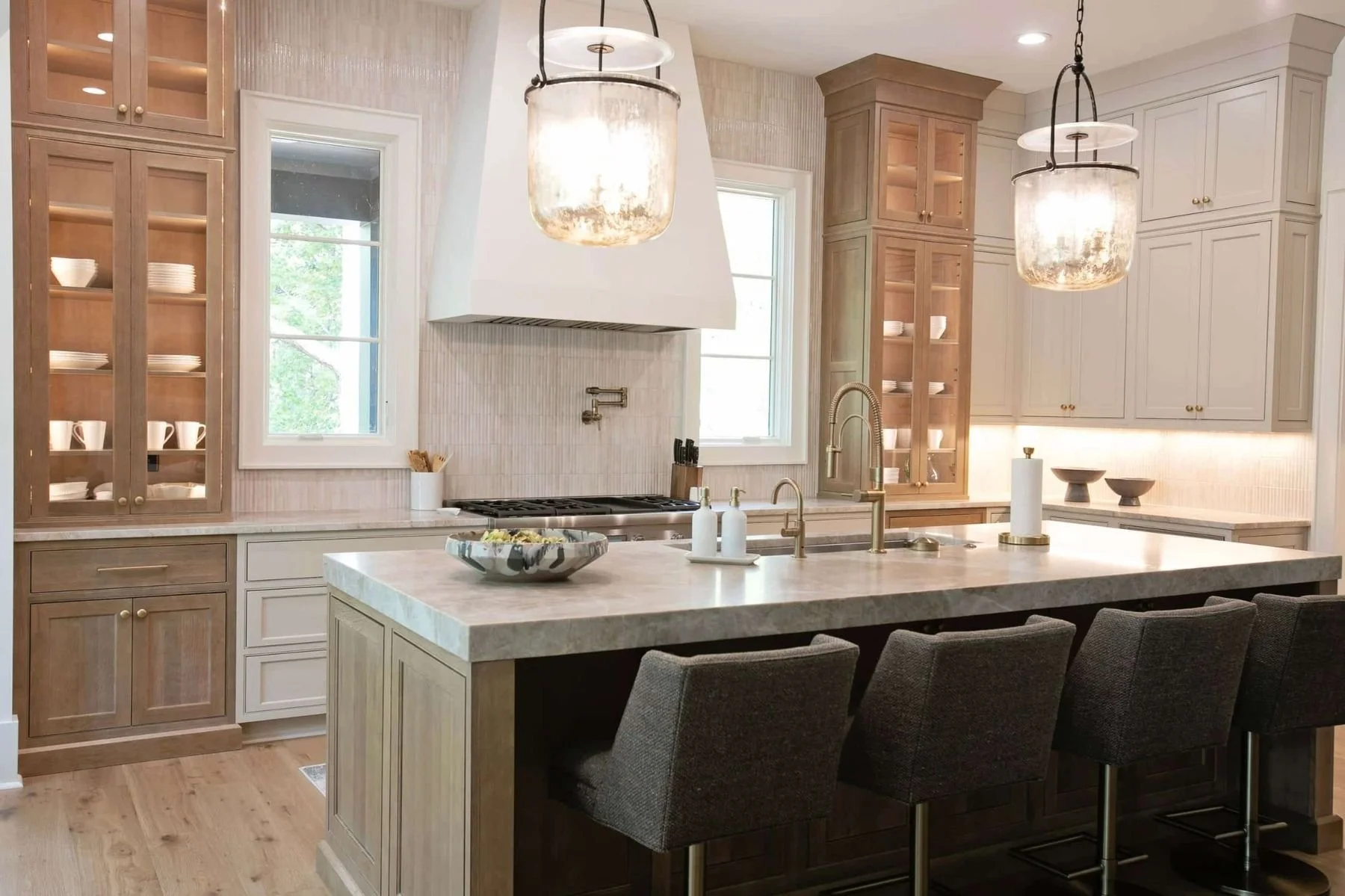 Custom kitchen cabinetry and hardwood flooring in a luxury Reynolds Lake Oconee home in Greensboro, Georgia. The kitchen features a large island with painted cabinetry, custom wood cabinets with glass-front display storage.