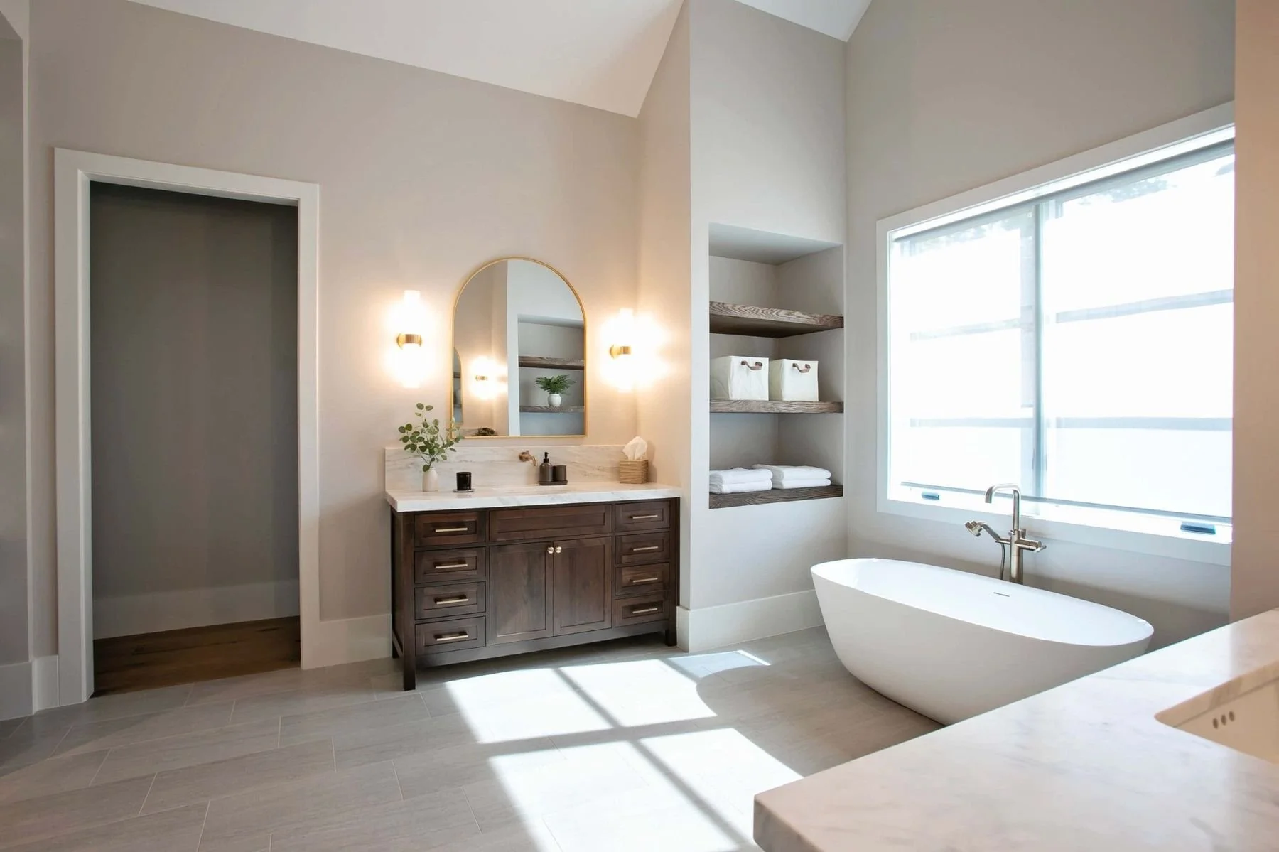 Custom bathroom cabinetry and tile flooring in a luxury Lake Oconee home in Greensboro, Georgia. The bathroom features a dark wood double vanity, quartz countertops, illuminated mirrors, freestanding soaking tub, and large windows that bring natural 