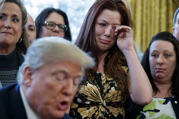 Victims of human trafficking, family members, and lawmakers listen as President Donald Trump speaks in the Oval Office at the White House before signing a new law aimed at curbing sex trafficking