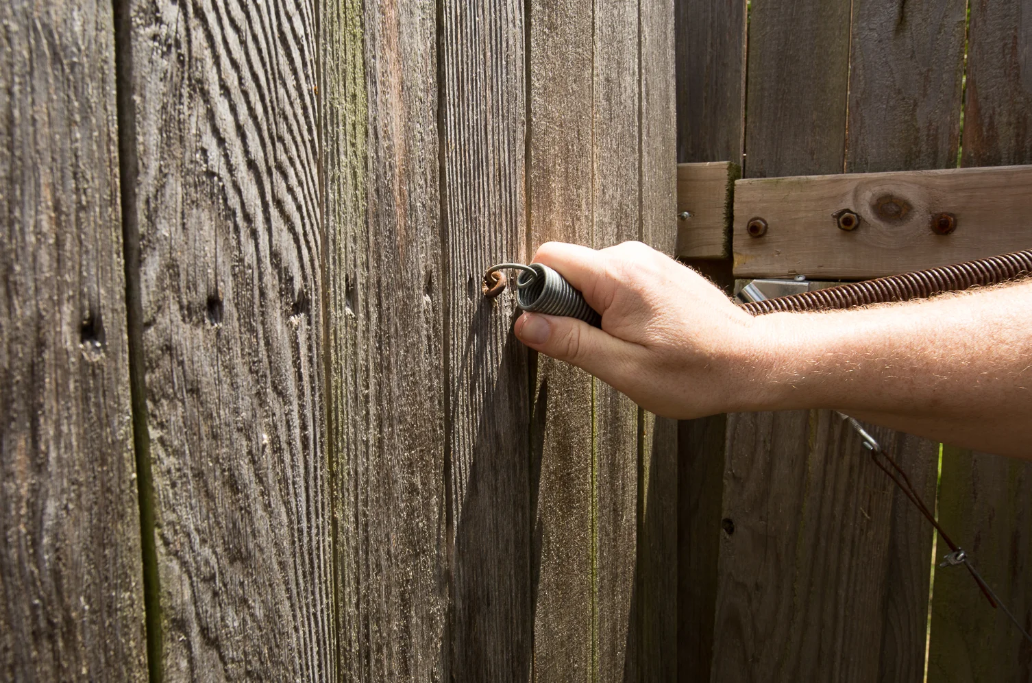 man fixes hinge of fence
