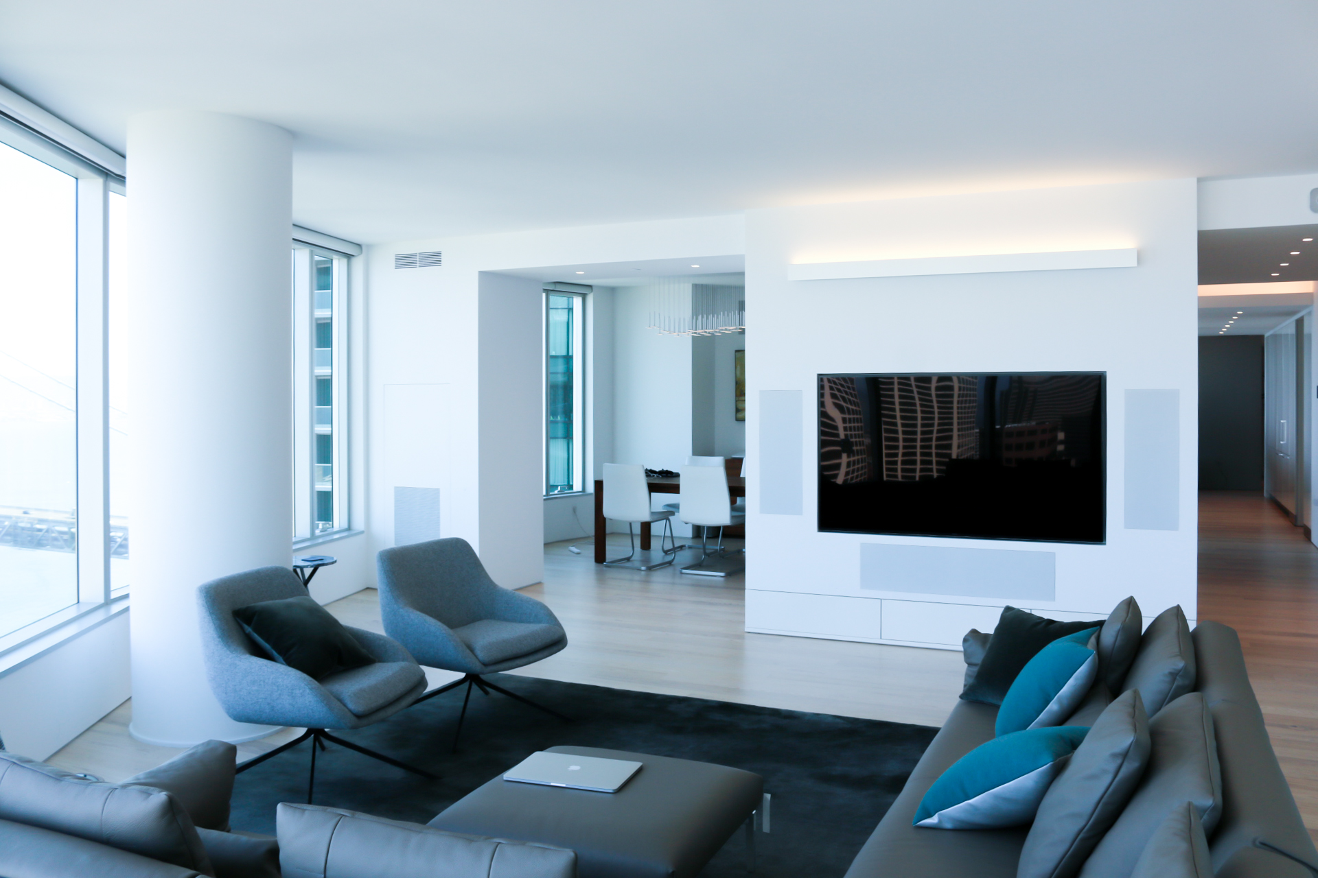 Tv recessed on white wall with speakers in a white living room