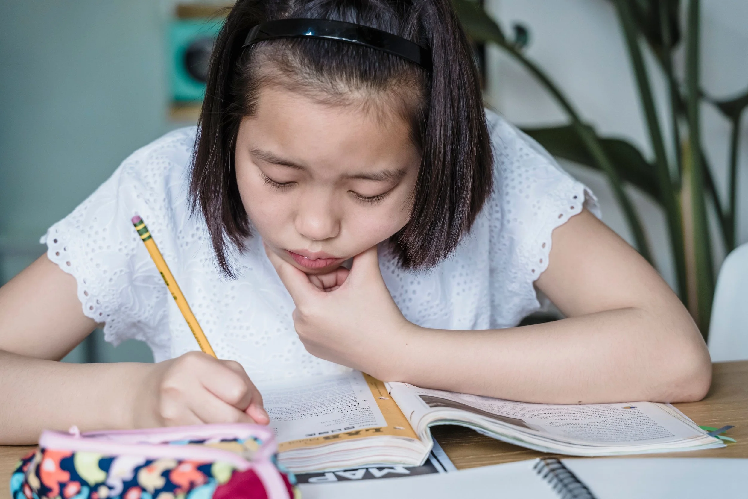 A young girl is trying to focus on her homework.