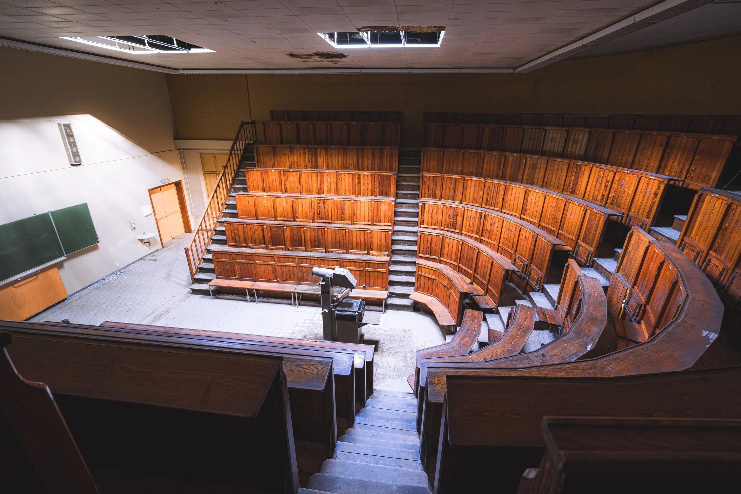 Empty vintage lecture hall with wooden seats and chalkboard, evoking Charles' experience of university with undiagnosed dyslexia.