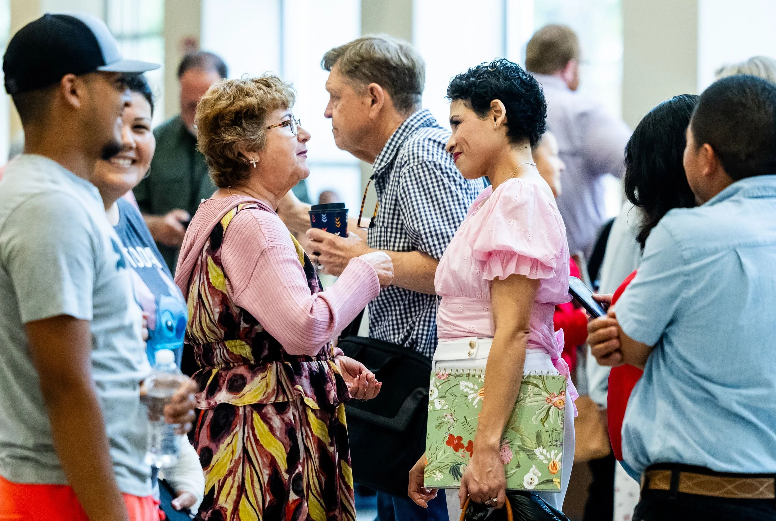 A diverse group of people engaging in friendly conversation at an indoor gathering, an example of social engagement.