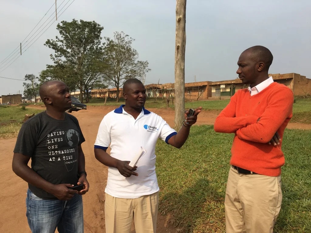 Picho and Collins talk with the leader of the Village Health Team in Kasambya.