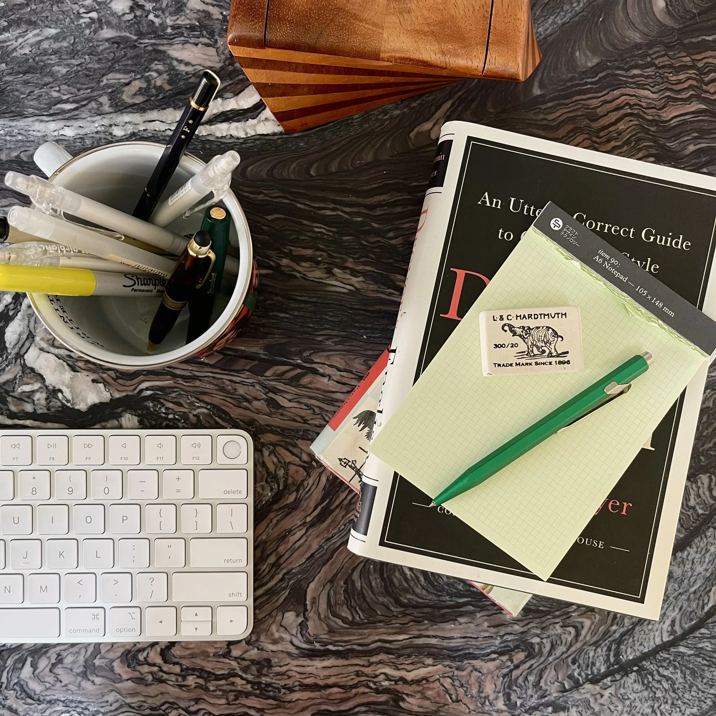 A marble desktop with books, a notepad, and a pencup