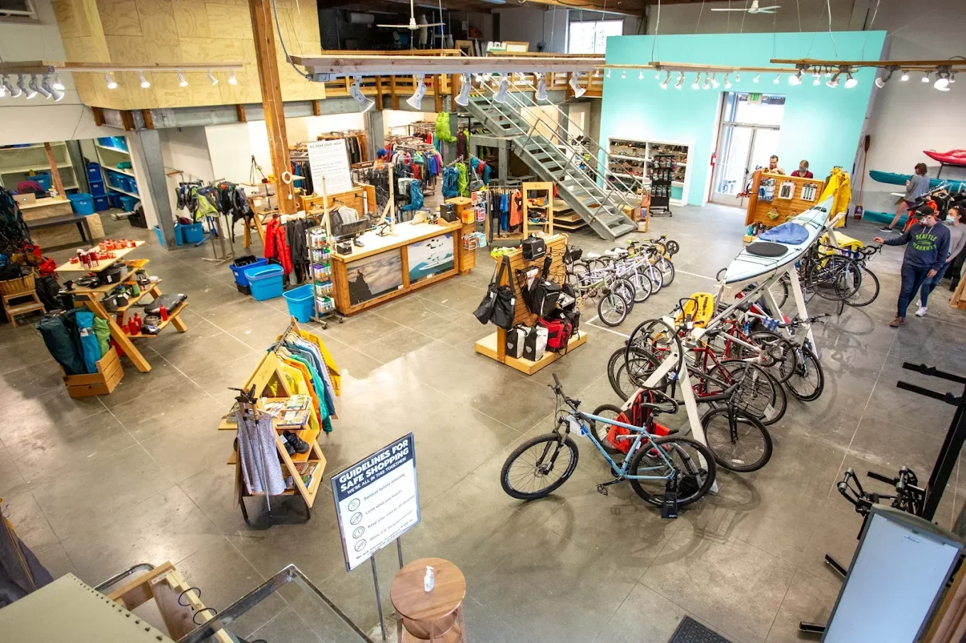 Interior of a retail store selling outdoor gear, including bicycles, kayaks, backpacks, and outdoor apparel.