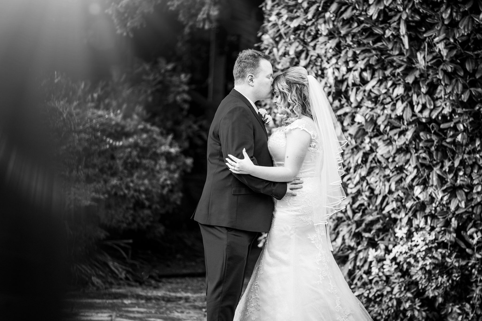 Bride and groom sunshine in gardens romantic kissing