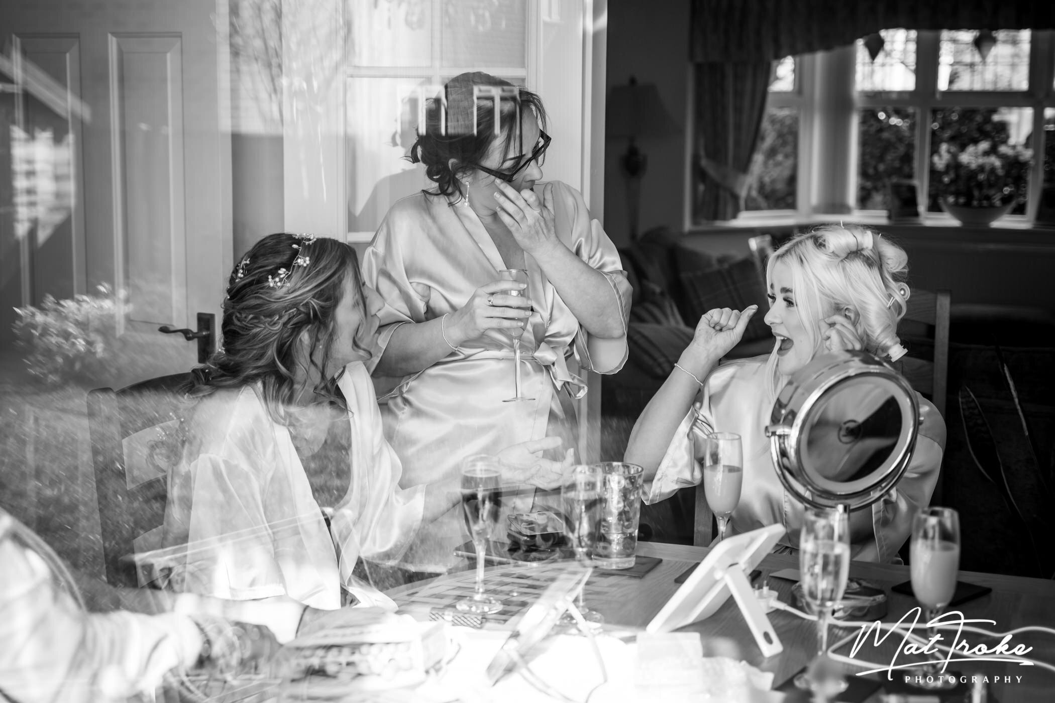 Reflection on window whilst bride and bridesmaids get ready for wedding car to arrive and go to venue