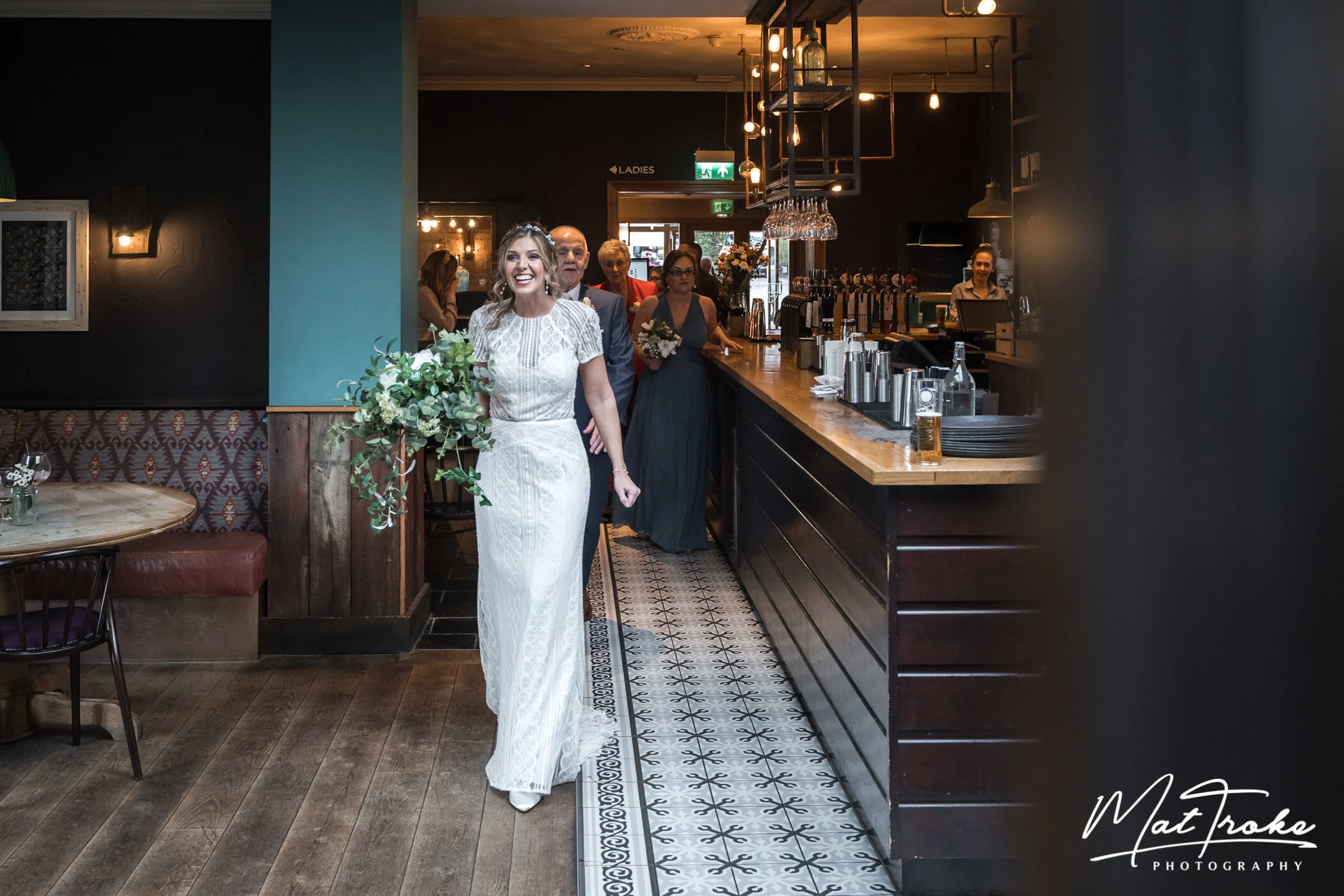 Bride and bridal party arriving for wedding ceremony in Farmhouse bar with father and bridesmaids