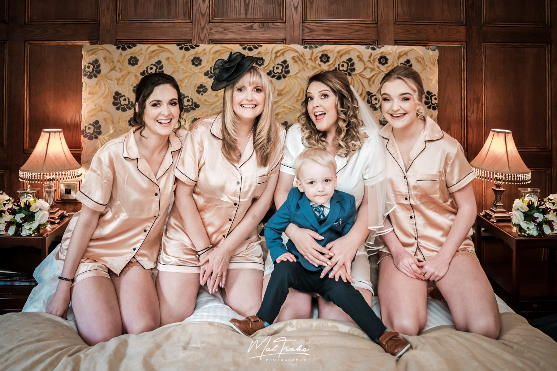 Bridal party on the bed in hotel room with matching gowns at Whitley Hall sheffield wedding
