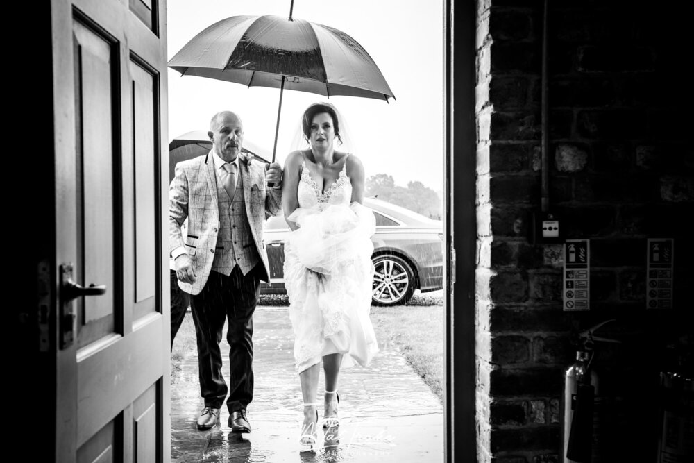holding-dress-bride-father-arriving-rain-wedding-raining-hazel-gap-barn-wedding.jpeg