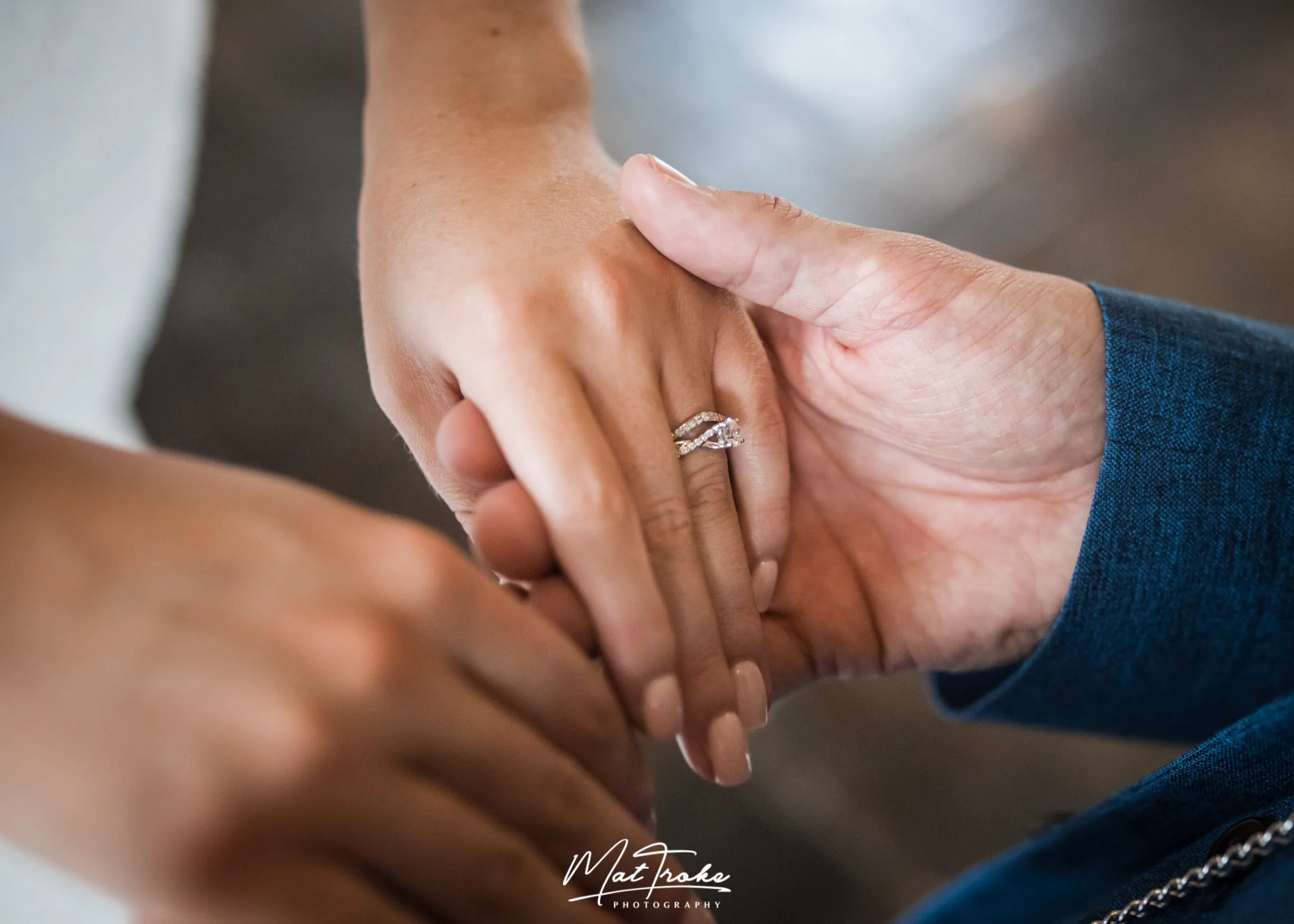 Bride and groom holding hands engagement ring