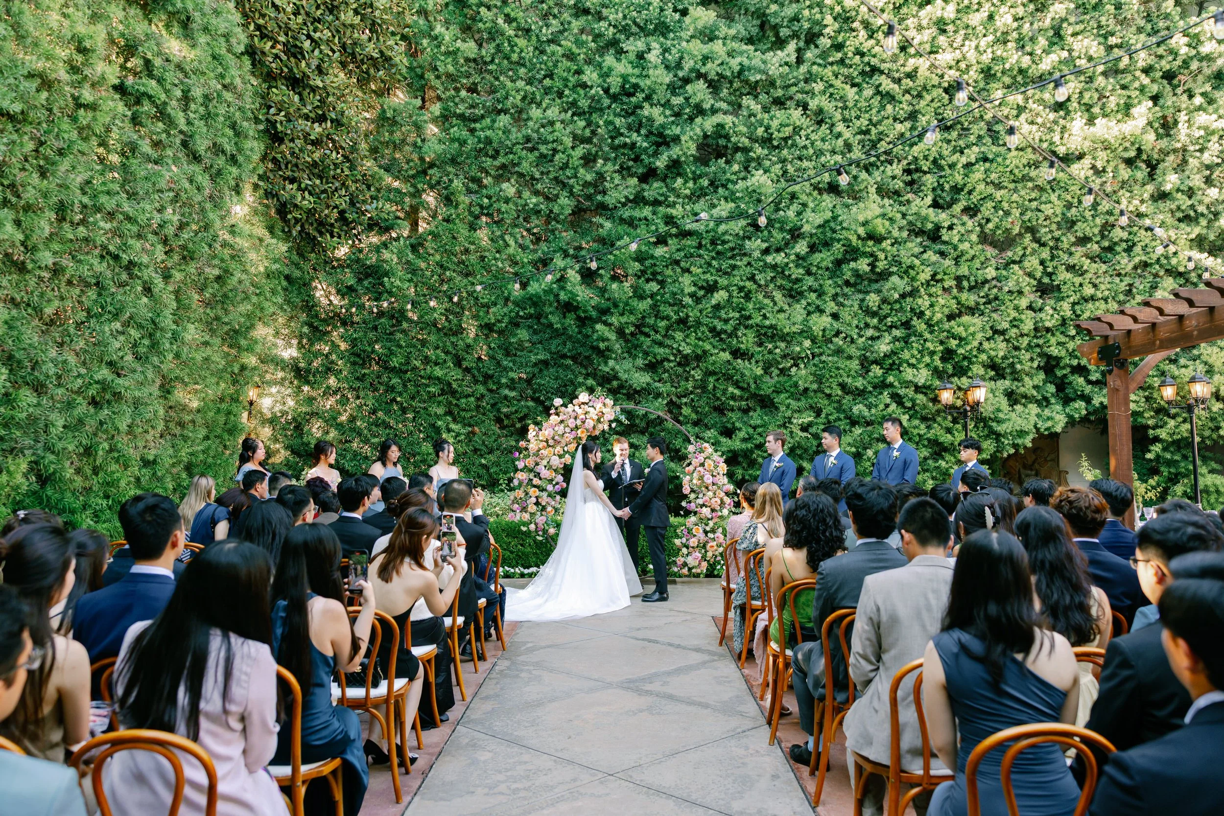 Outdoor wedding ceremony at Franciscan Gardens in San Juan Capistrano with floral arch and garden setting