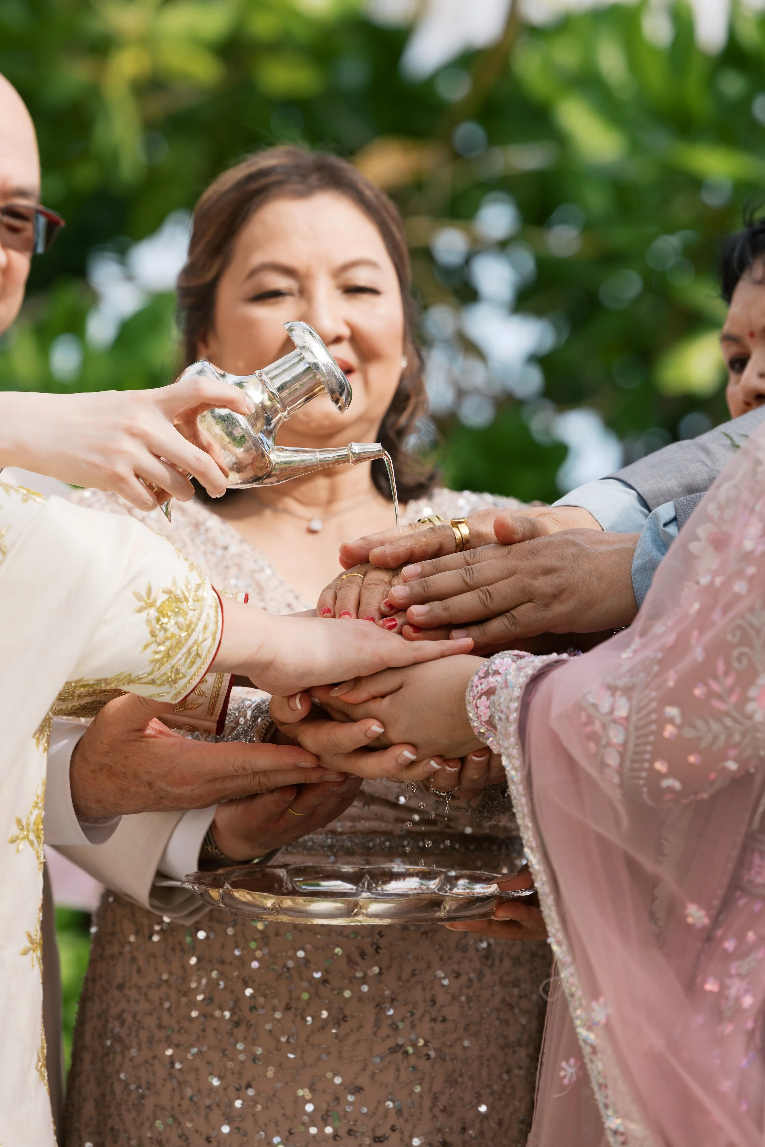 People participating in a traditional cultural ceremony, with one person pouring water onto another's hands.