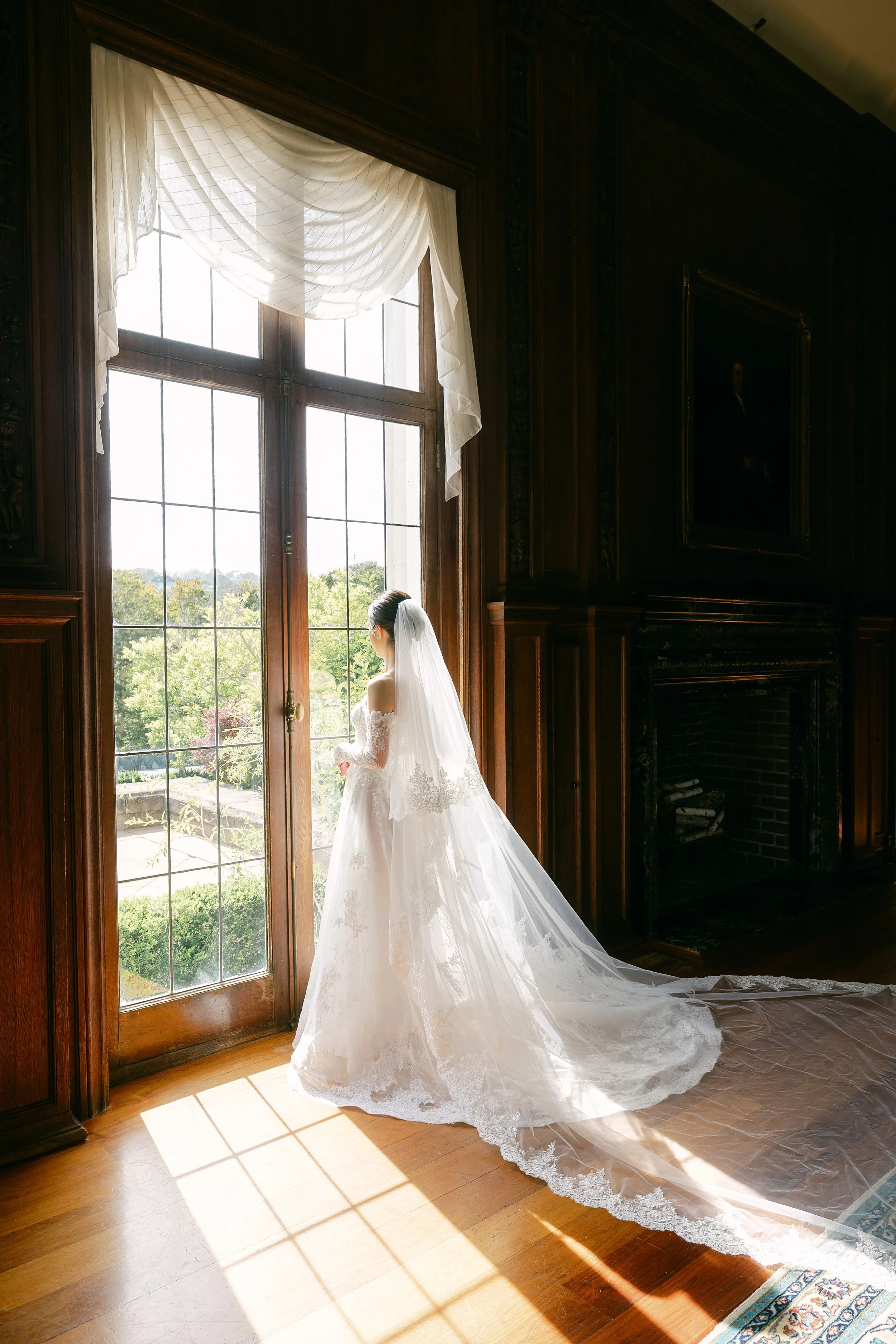 A bride and groom celebrating at their wedding outdoors. The groom is lifting the bride, who is holding a bouquet of flowers, in front of a natural backdrop of trees and greenery.