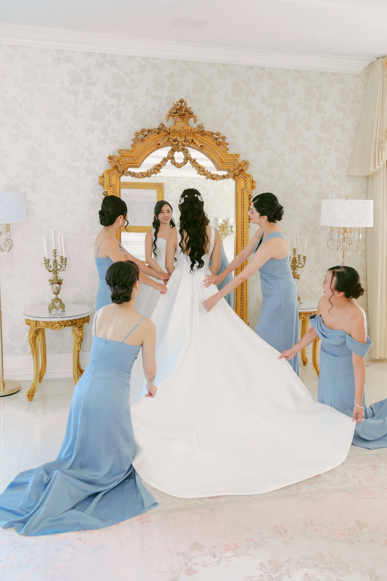 Bridesmaids helping the bride with her wedding dress inside Château de Michellia in Salem, Oregon.